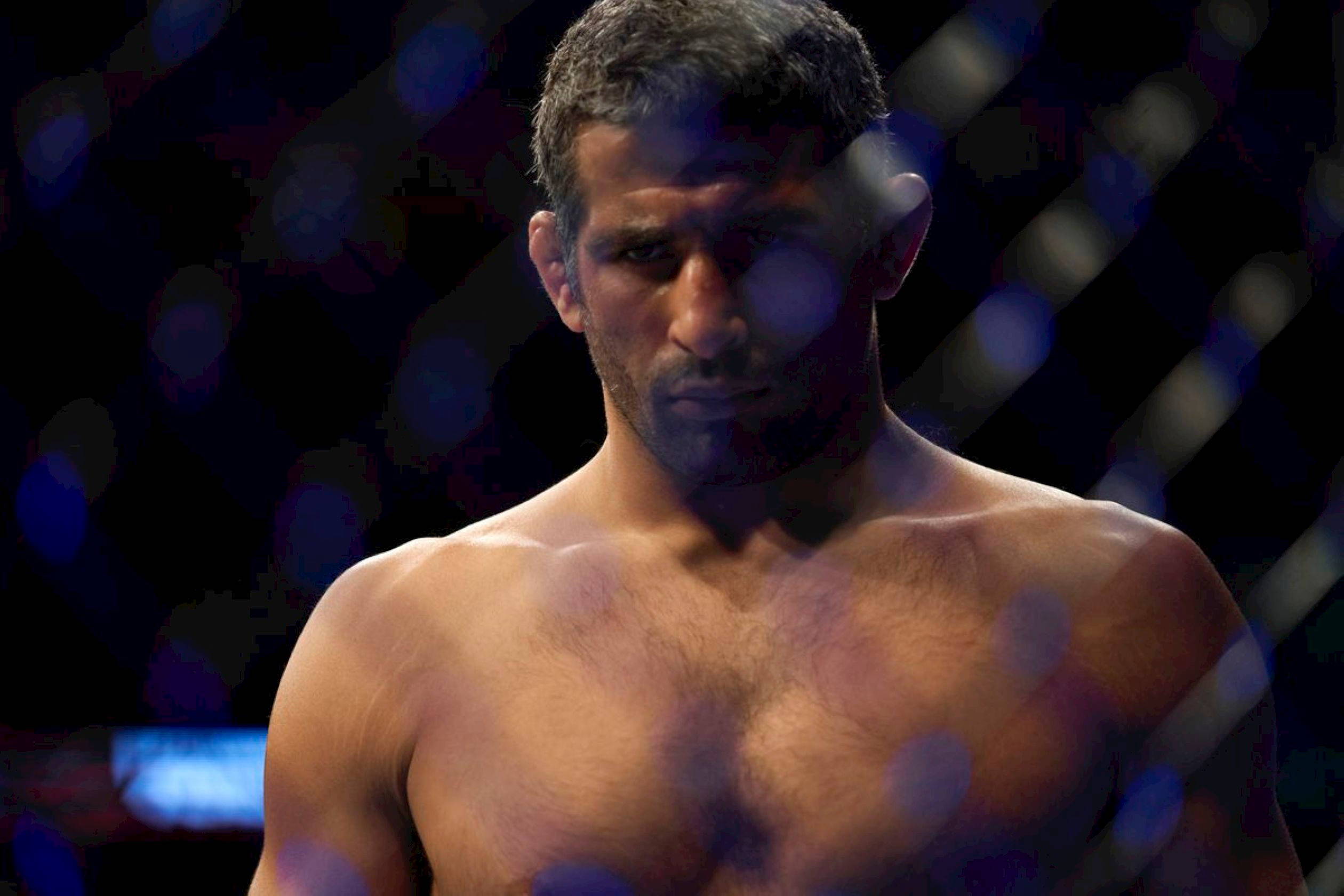 UFC 桌布 壁紙 — 一位專注的混合武術選手在昏暗的八角籠內，背景有模糊的藍光，眼神銳利。