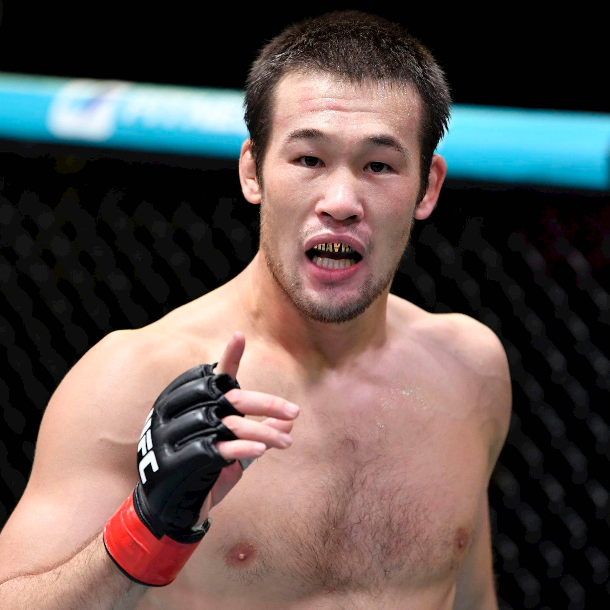 UFC 桌布 壁紙 — 一位專注的混合武術選手在格鬥籠中，戴著黑色手套和紅色腕帶。