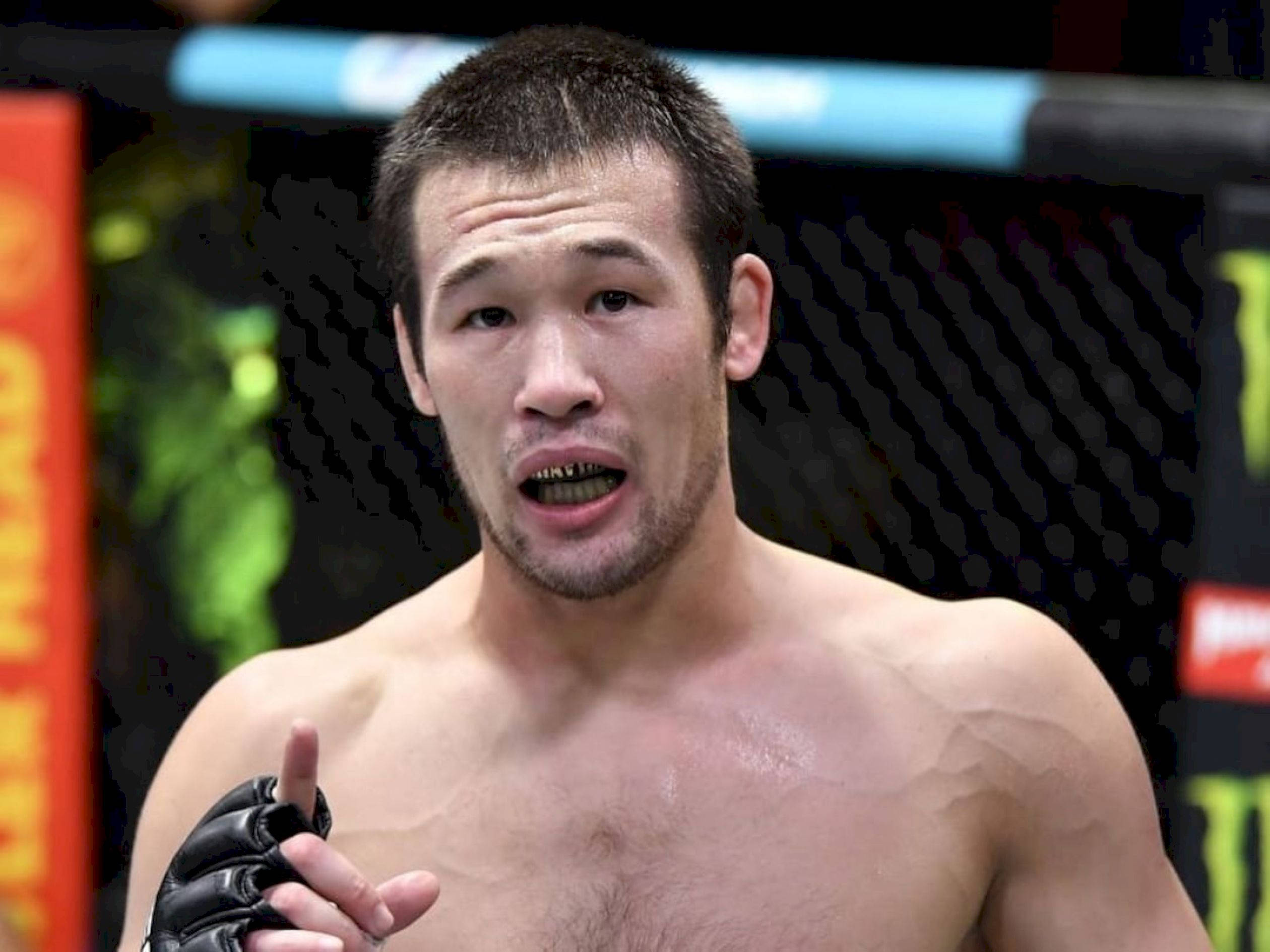 UFC 桌布 壁紙 — 一位專注的混合武術選手在籠中比賽時堅定地指向前方。
