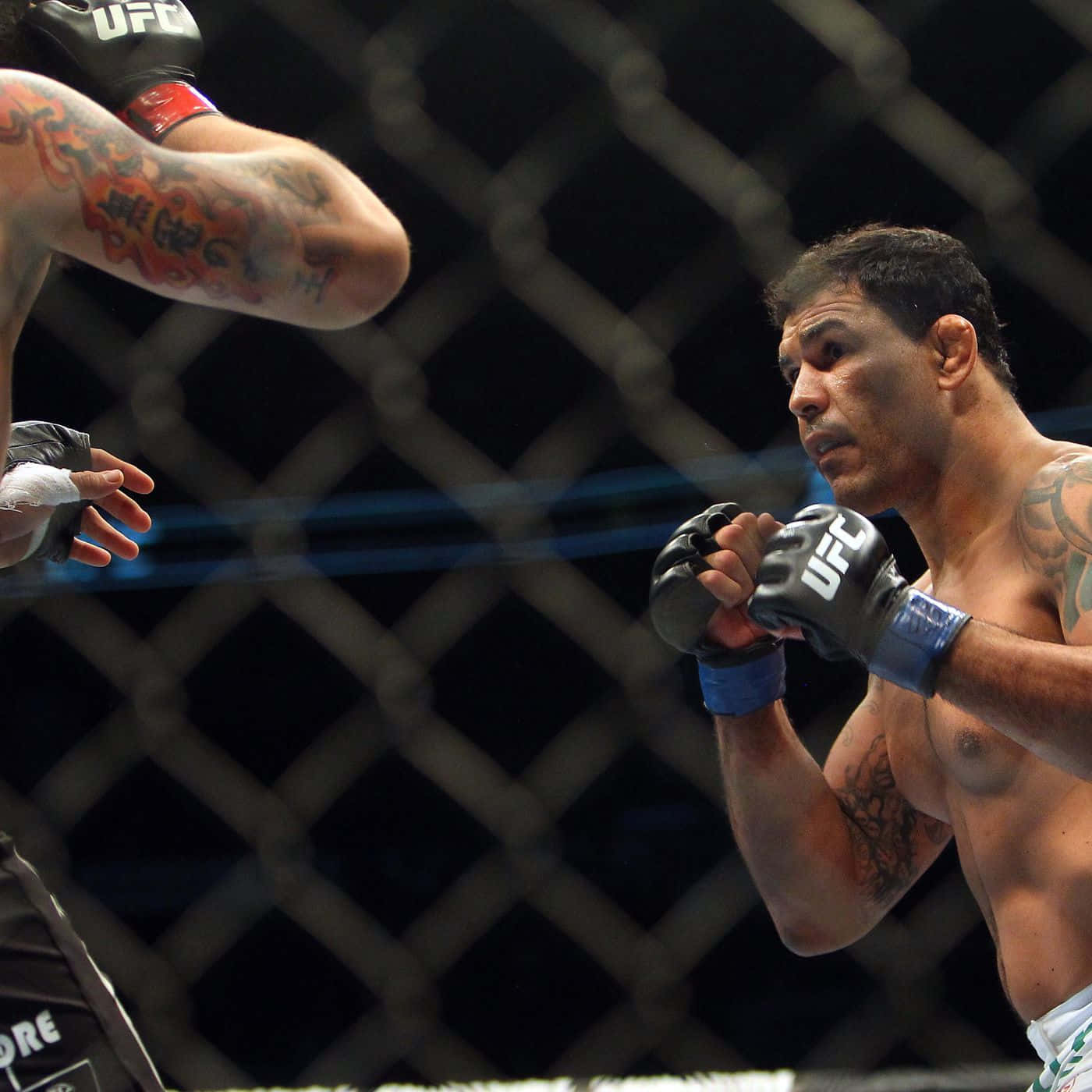 MMA 桌布 壁紙 — 一位專注的混合武術選手戴上UFC手套，在八角籠內為高風險比賽中的衝擊做好準備。