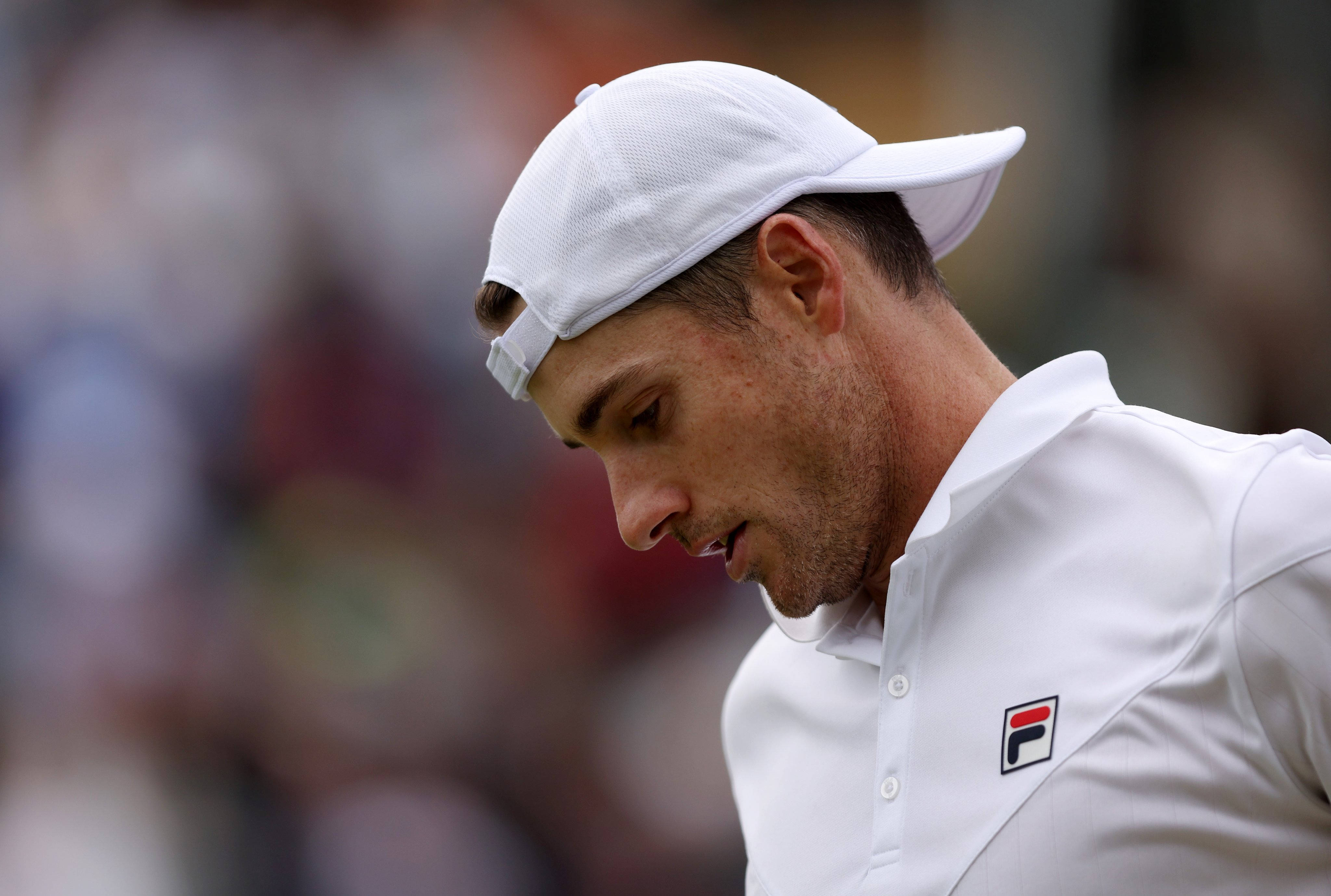 Tennis 桌布 壁紙 — 一位專注的男性網球運動員，戴著白色帽子和穿著白色襯衫，在比賽中專注地低頭。