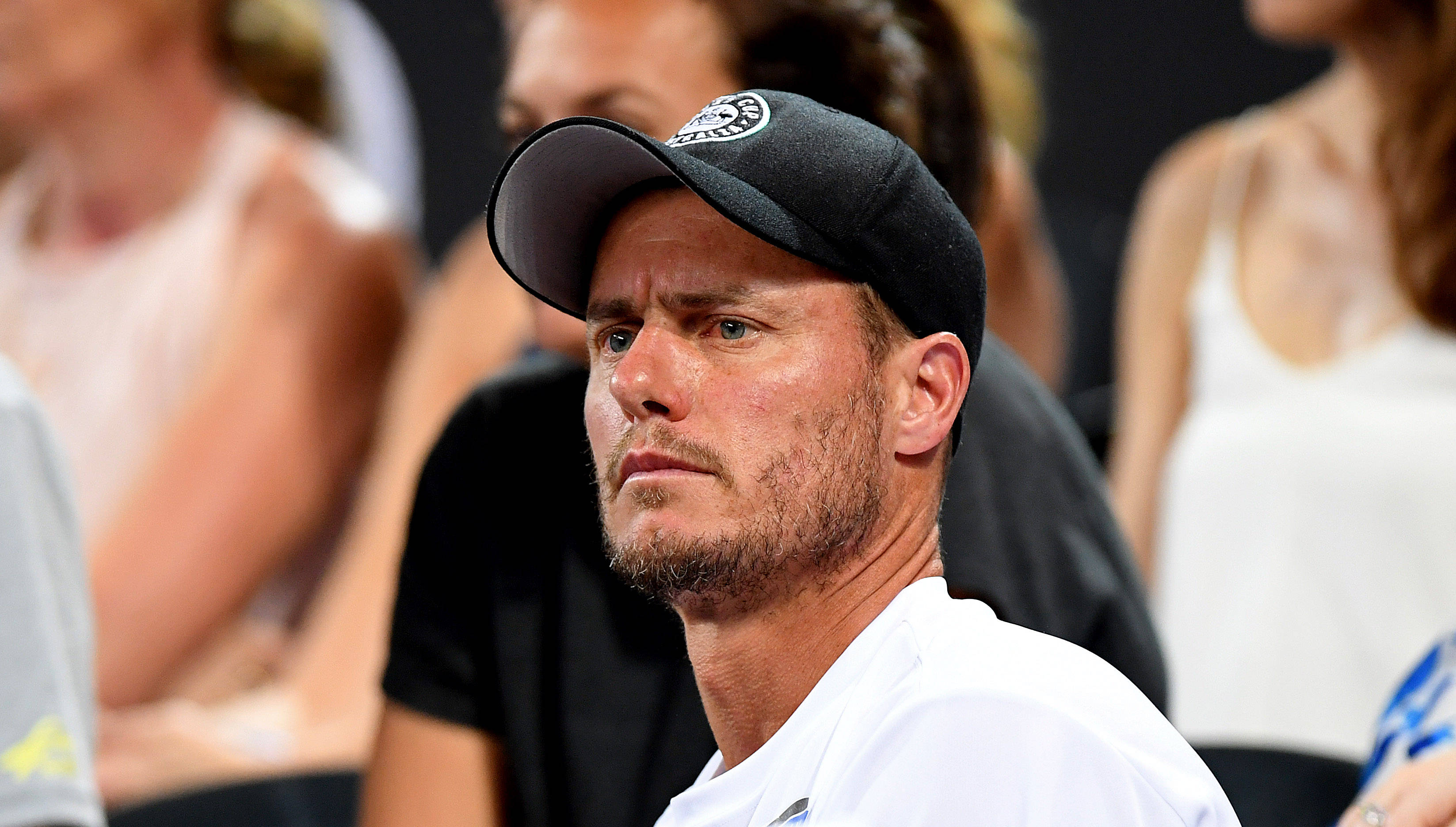 Australian Open 桌布 壁紙 — 一位專注的男性網球運動員，戴著黑色帽子，穿著白色襯衫，在比賽中凝視著，背景是模糊的觀眾。