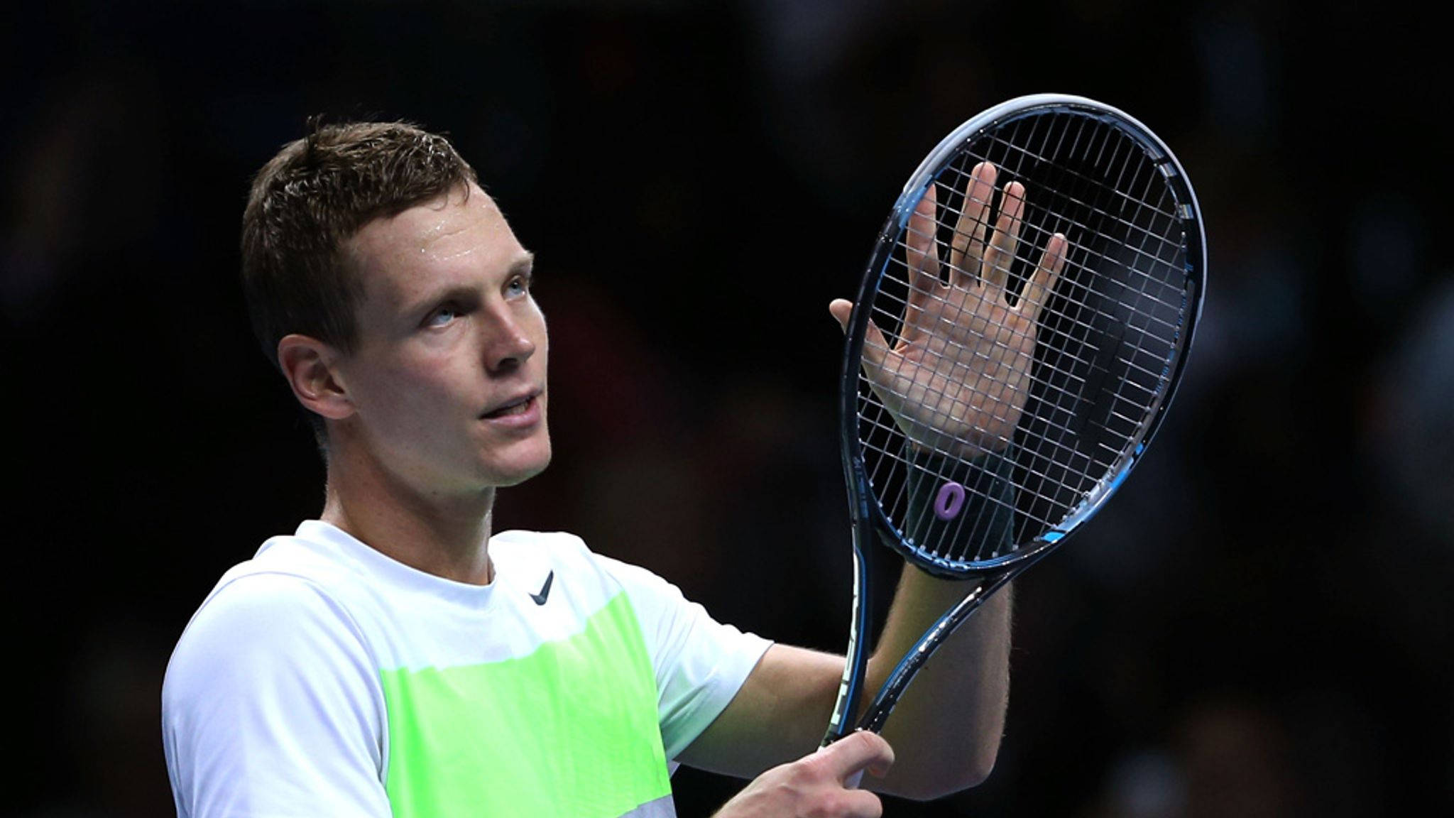 Tennis 桌布 壁紙 — 一位專注的男性網球運動員，身穿白色和螢光綠色襯衫，在明亮燈光下的體育館中單手高舉球拍。