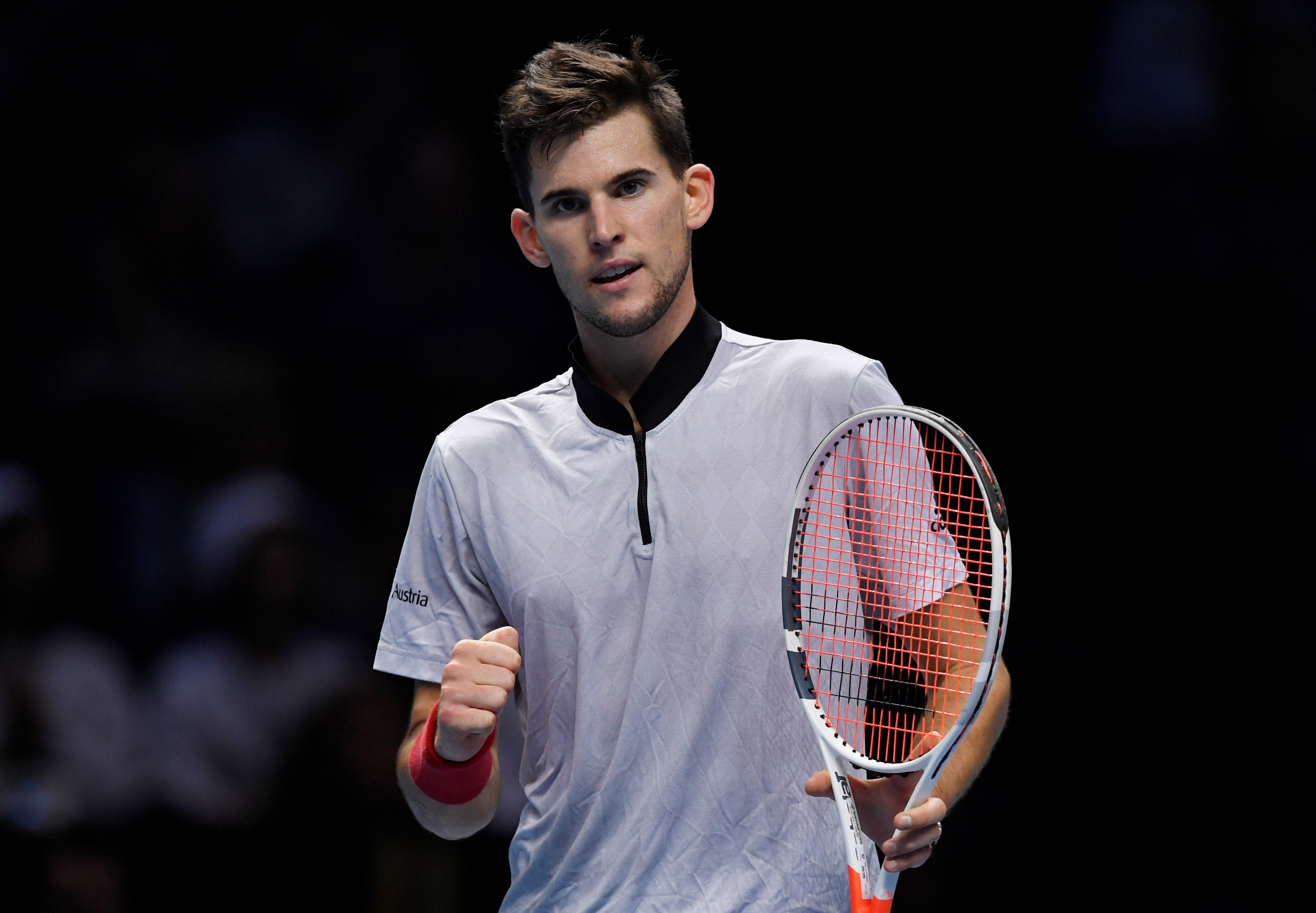 dominic thiem 桌布 壁紙 — 一位專注的男性網球運動員在競技場燈光下握緊拳頭慶祝，手中握著球拍。