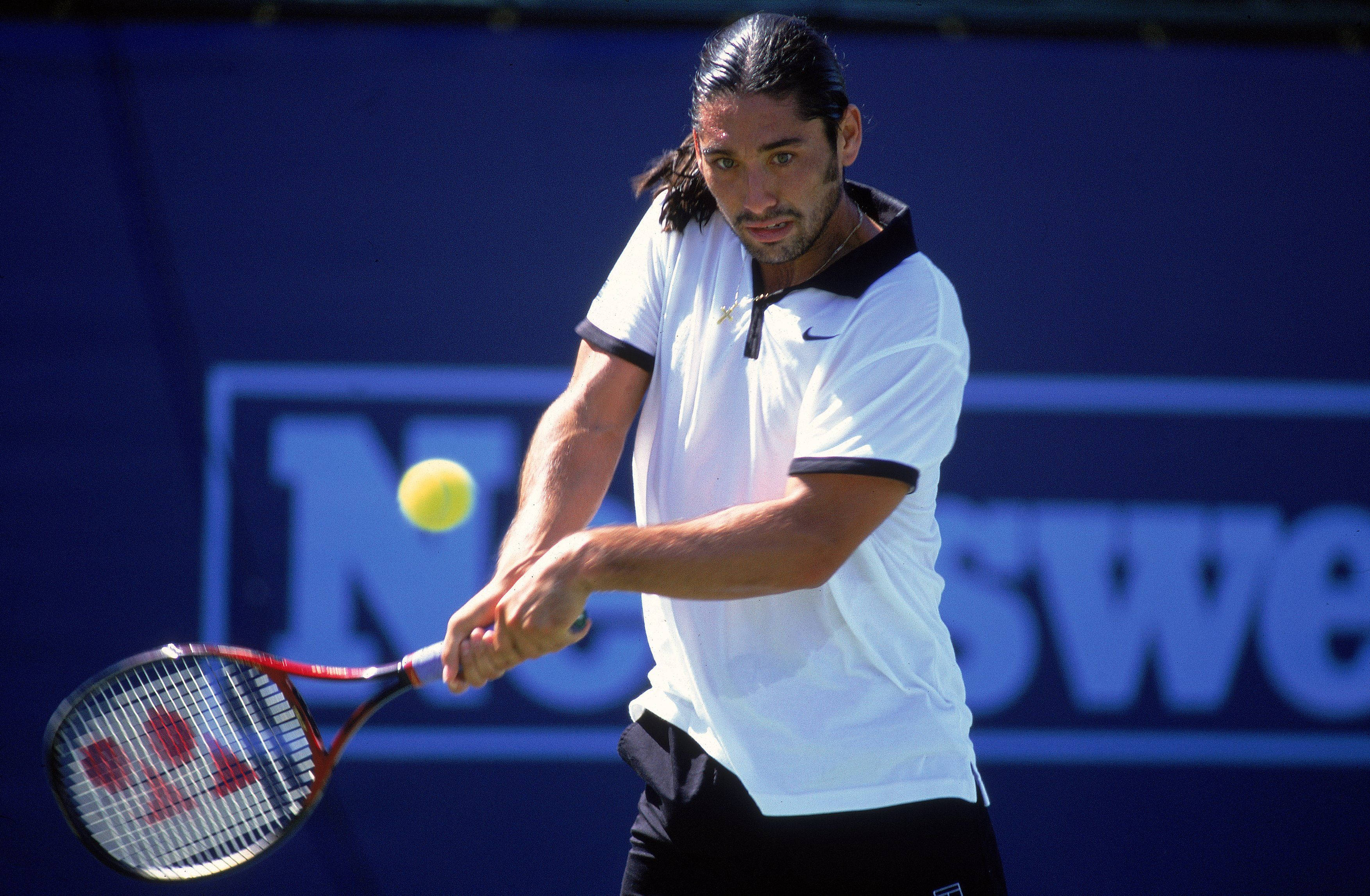 Tennis 桌布 壁紙 — 一位專注的男性網球運動員在藍色球場背景下揮拍擊打黃色網球。