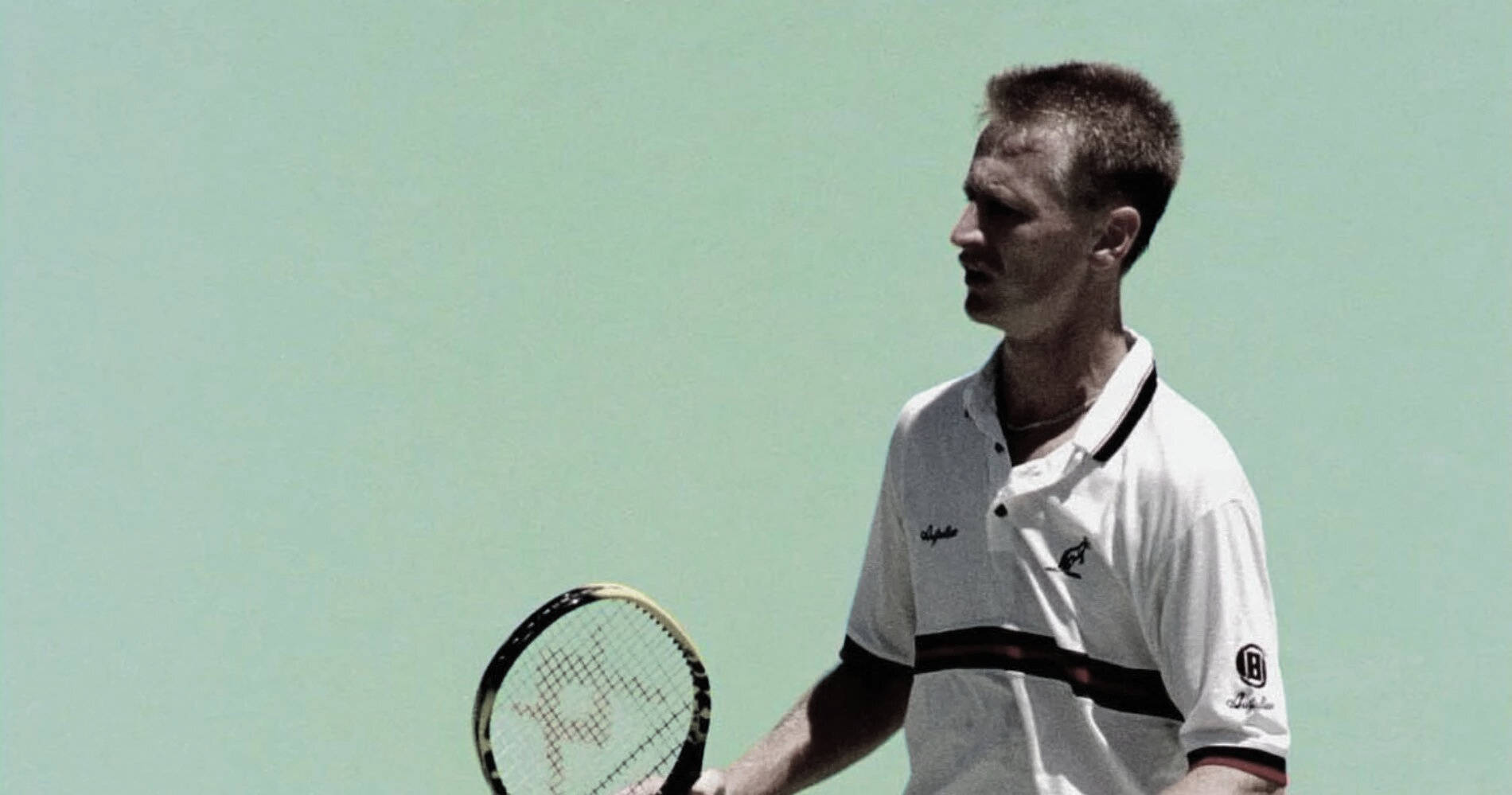 Tennis 桌布 壁紙 — 一位專注的男性網球運動員穿著白色Polo衫，在純淺綠色背景前握著球拍。