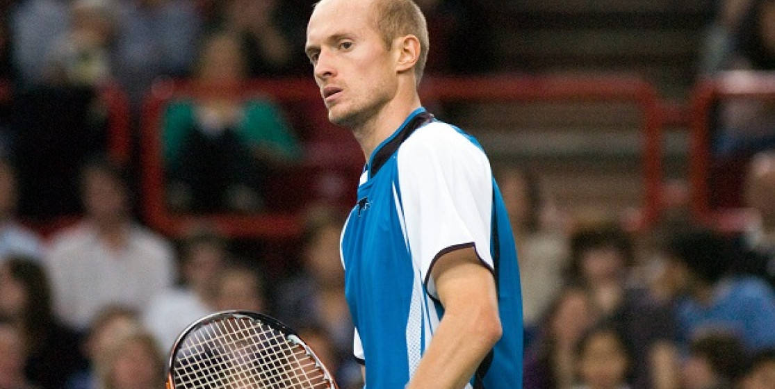 Tennis 桌布 壁紙 — 一位專注的男性網球運動員身穿藍白襯衫，在比賽中握著球拍，背景有模糊的觀眾。