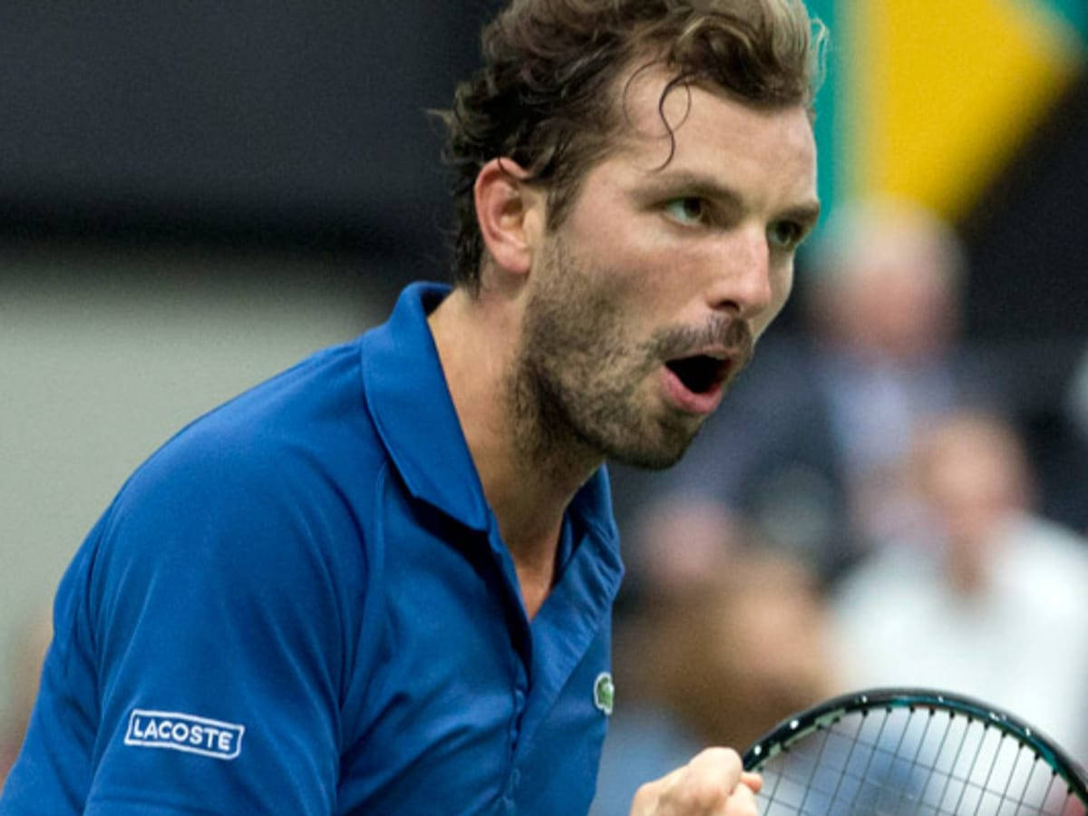 Tennis 桌布 壁紙 — 一位專注的男性網球運動員身穿藍色Lacoste襯衫，在室內激烈比賽中大喊。