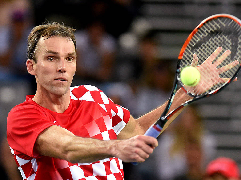 Tennis 桌布 壁紙 — 一位專注的男性網球選手，身穿紅白格子衫，在比賽中揮拍擊打明亮的黃色網球。