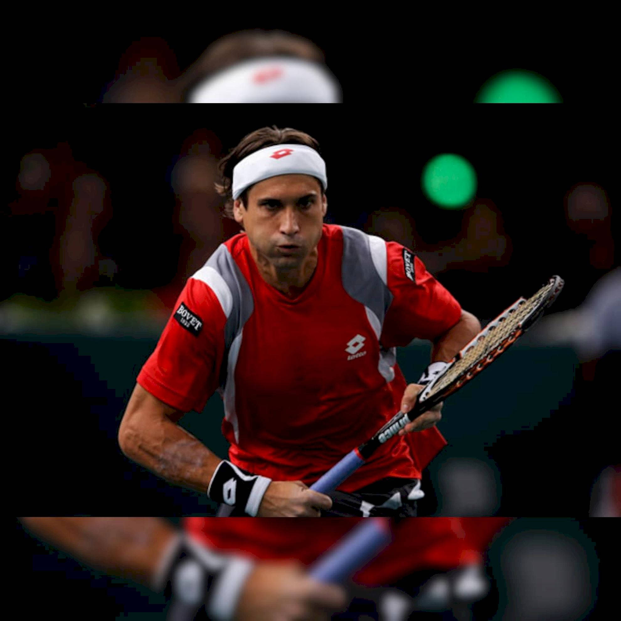 Athletic 桌布 壁紙 — 一位專注的男性網球選手，身穿紅色和灰色裝備，在黑暗模糊的背景下，綠色燈光中，揮拍中途緊握球拍。