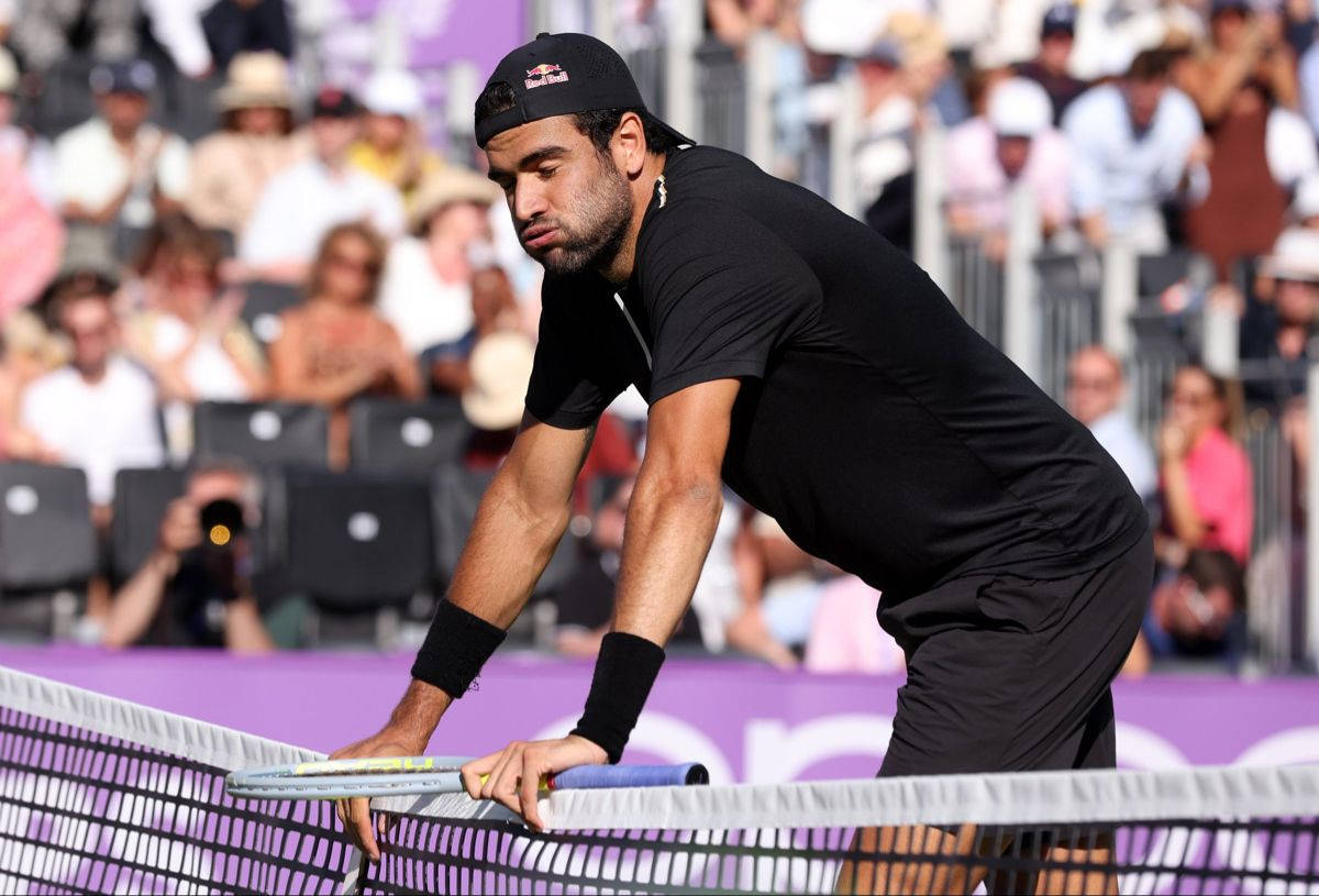 Tennis 桌布 壁紙 — 一位專注的男性網球選手在比賽中俯身越過球網，緊握球拍，背景有觀眾。