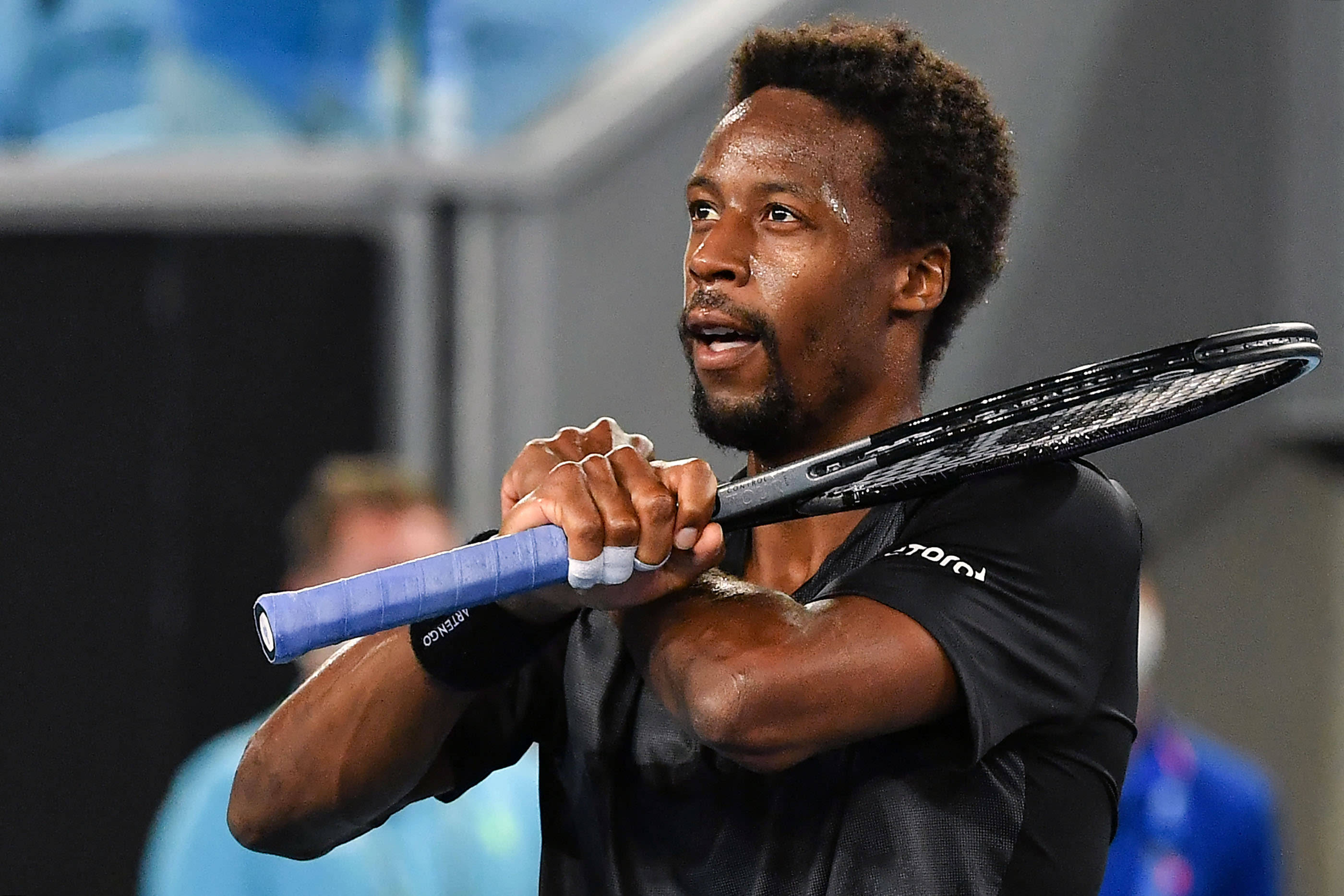 Tennis 桌布 壁紙 — 一位專注的男性網球選手在比賽中揮拍中途緊握球拍，神情高度集中。