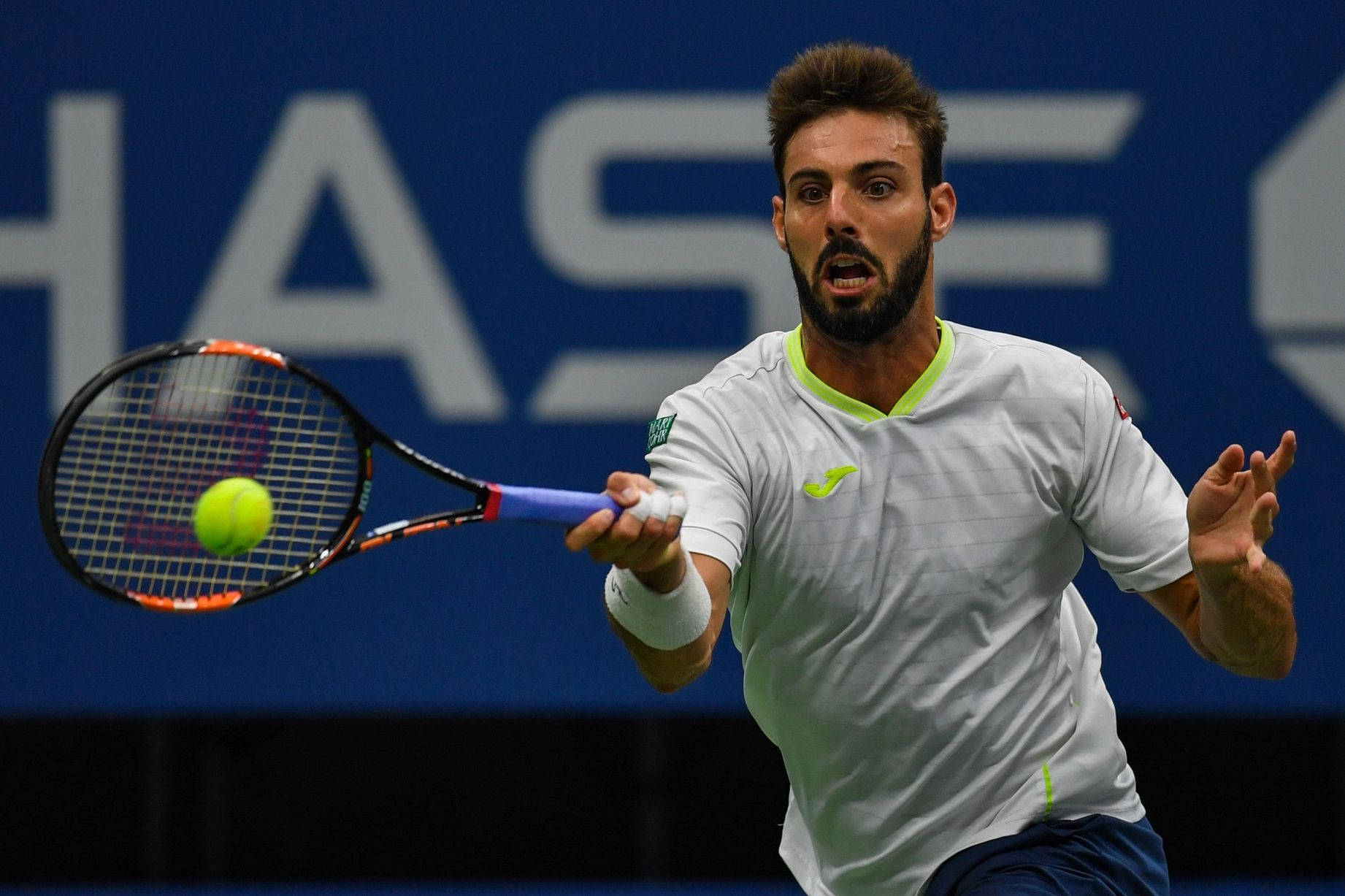 Tennis 桌布 壁紙 — 一位專注的男性網球選手在激烈的比賽中揮動球拍擊打一顆亮黃色的球。