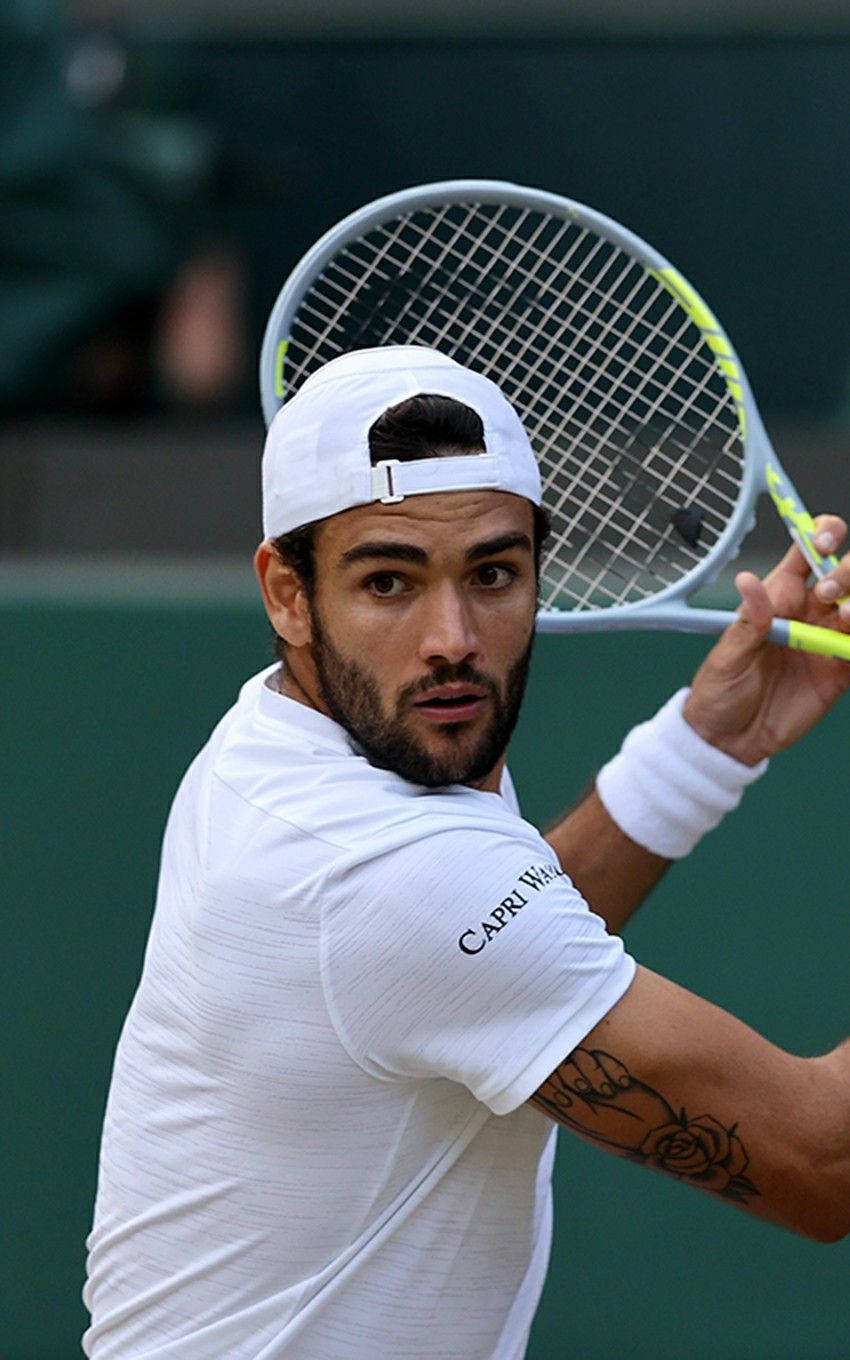 Tennis 桌布 壁紙 — 一位專注的男性網球選手穿著白色裝備，在綠色球場上以強烈的專注力揮拍。