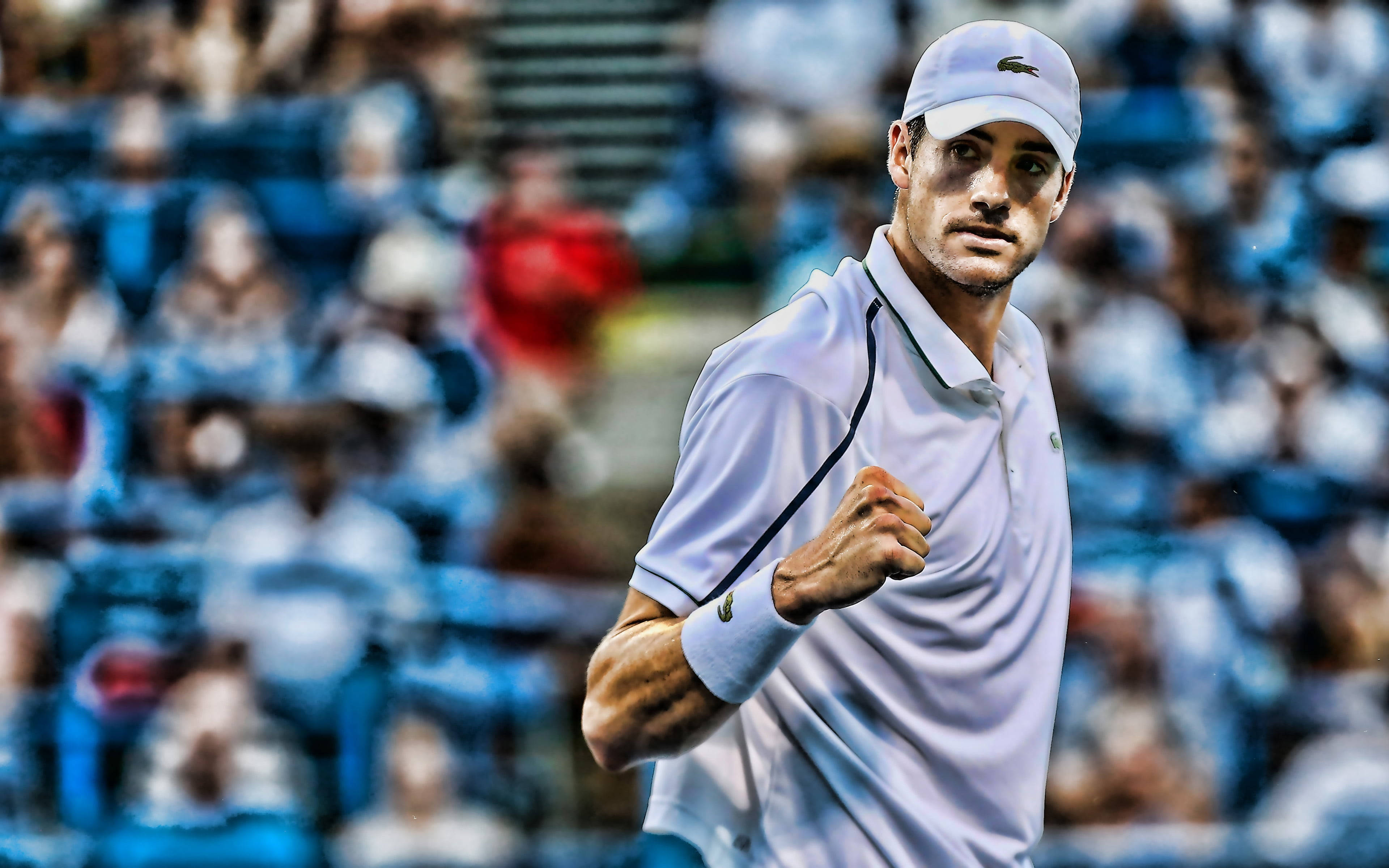 Tennis 桌布 壁紙 — 一位專注的男性網球選手穿著白色裝備，在模糊的人群背景中於比賽中握緊拳頭。
