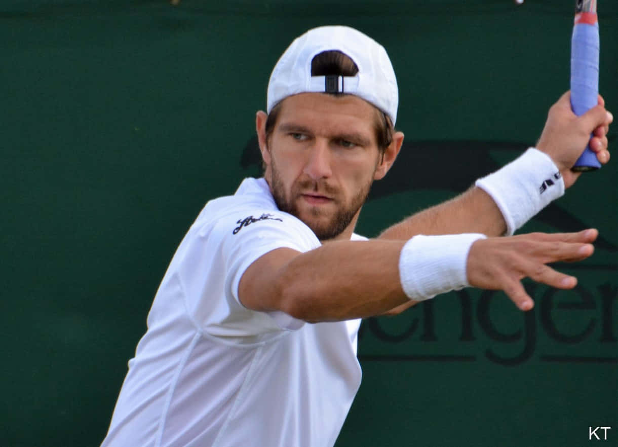 Tennis 桌布 壁紙 — 一位專注的男性網球選手穿著白色裝備，在綠色球場背景下揮拍。