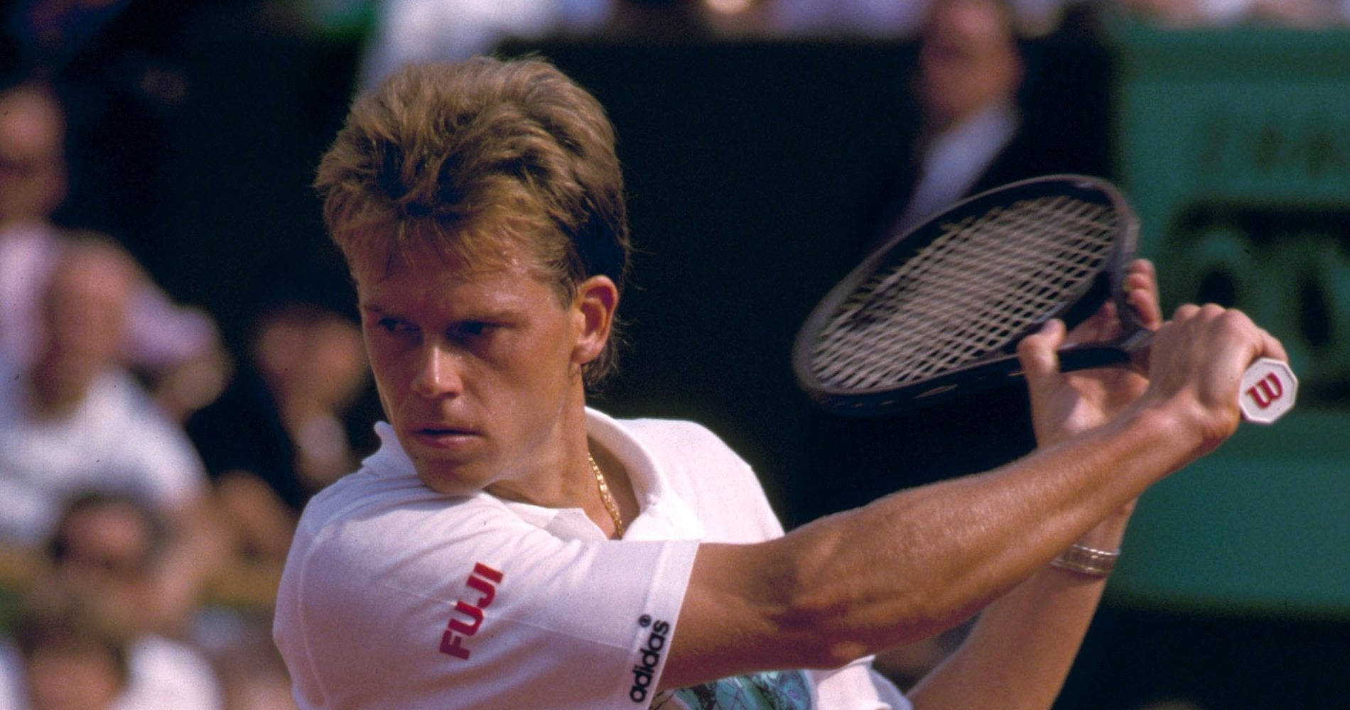 Tennis 桌布 壁紙 — 一位專注的男性網球選手穿著白色襯衫，在比賽中揮動球拍，背景有模糊的觀眾。