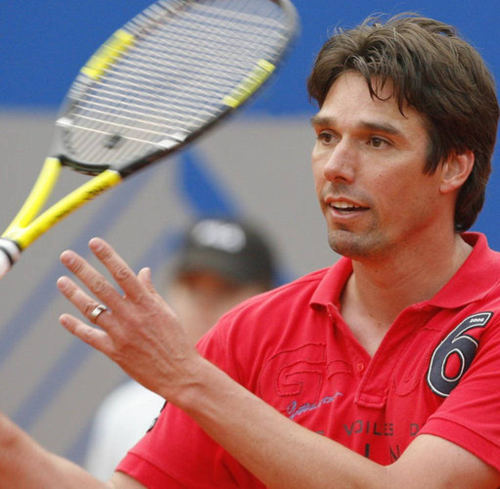 Tennis 桌布 壁紙 — 一位專注的男性網球選手穿著紅色襯衫，在比賽中揮動黃色球拍，神情專注。