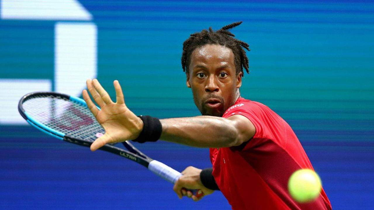 Tennis 桌布 壁紙 — 一位專注的男性網球選手穿著紅色襯衫，在藍色球場背景下揮拍擊打黃色球。