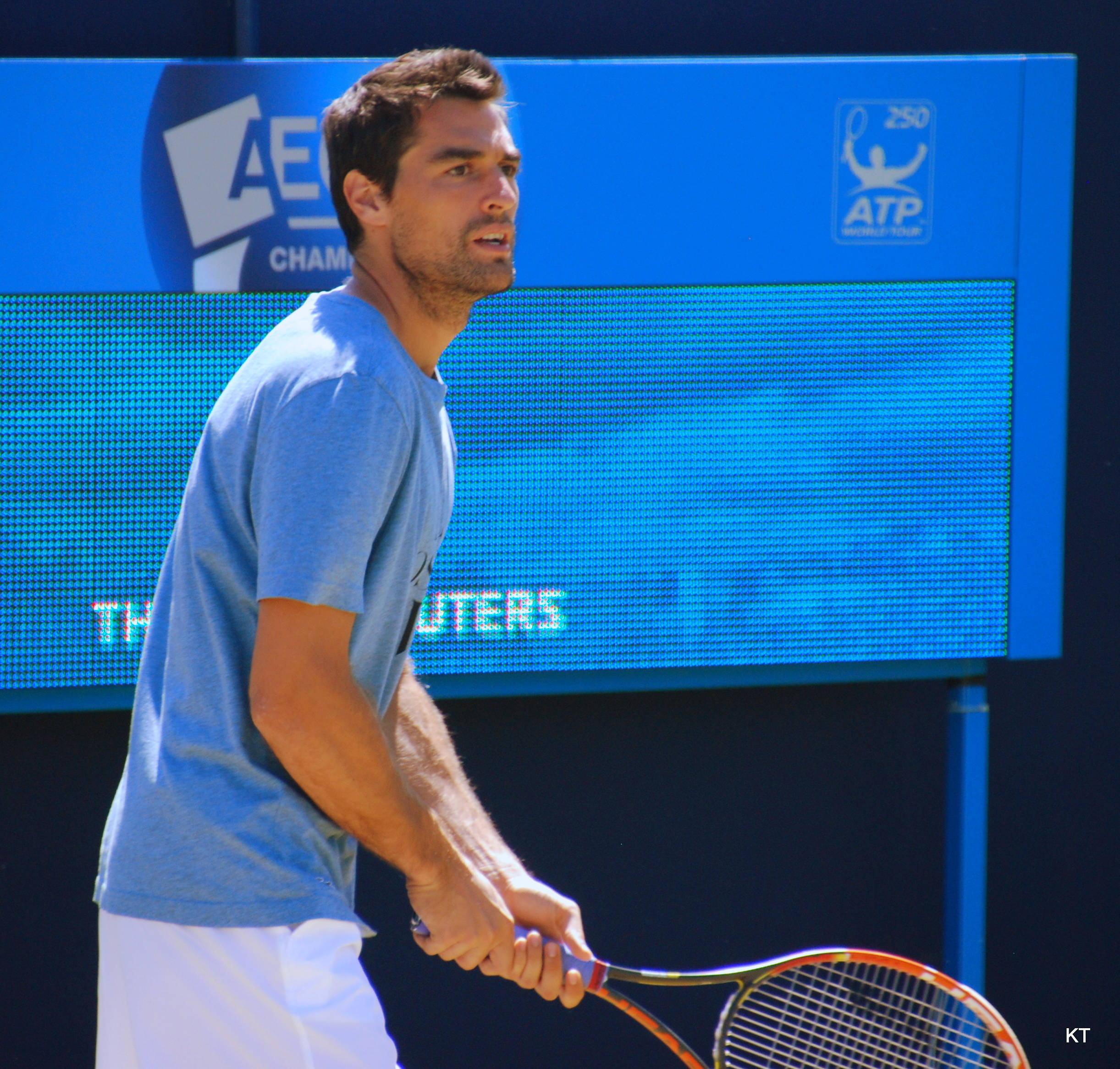 Tennis 桌布 壁紙 — 一位專注的男性網球選手身穿淺藍色襯衫，在充滿活力的藍色ATP錦標賽背景下，比賽中緊握球拍。