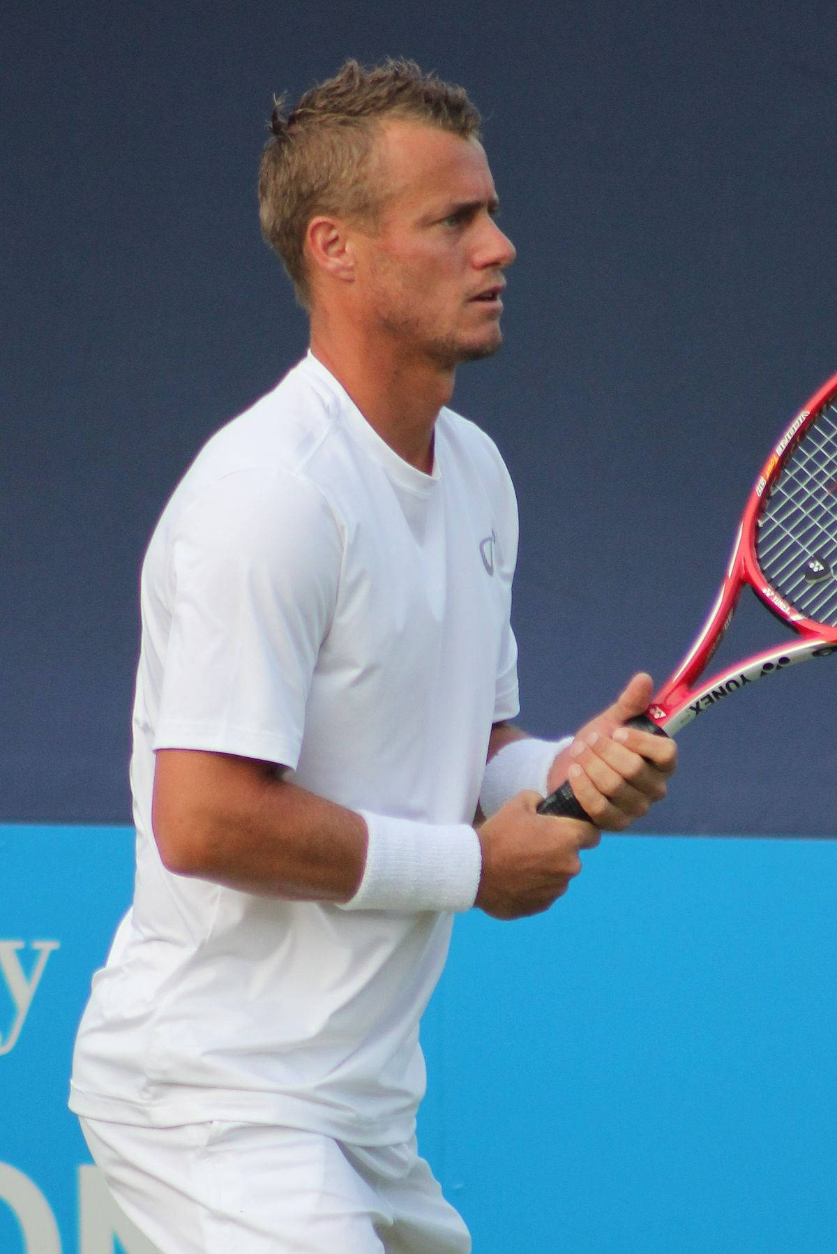 Australian Open 桌布 壁紙 — 一位專注的男性網球選手身穿白色裝備，在藍色球場背景下握著紅色球拍。