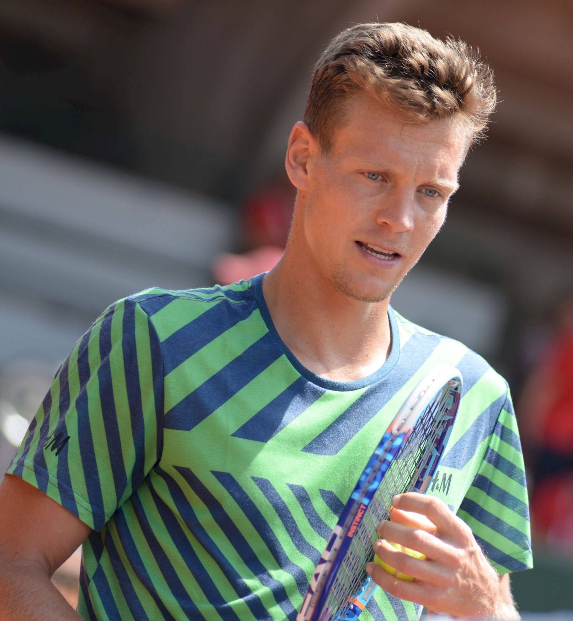 Tennis 桌布 壁紙 — 一位專注的男網球運動員，身穿綠色和藍色條紋襯衫，在日間比賽中握著球拍。