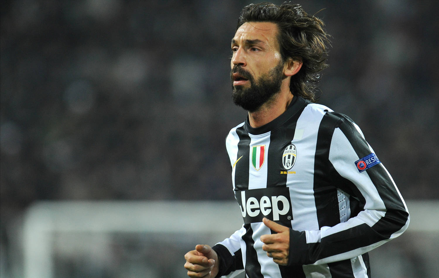 andrea pirlo 桌布 壁紙 — 一位專注的祖雲達斯足球員身穿黑白間條球衣，在球場燈光下於夜間比賽中激烈奔跑。