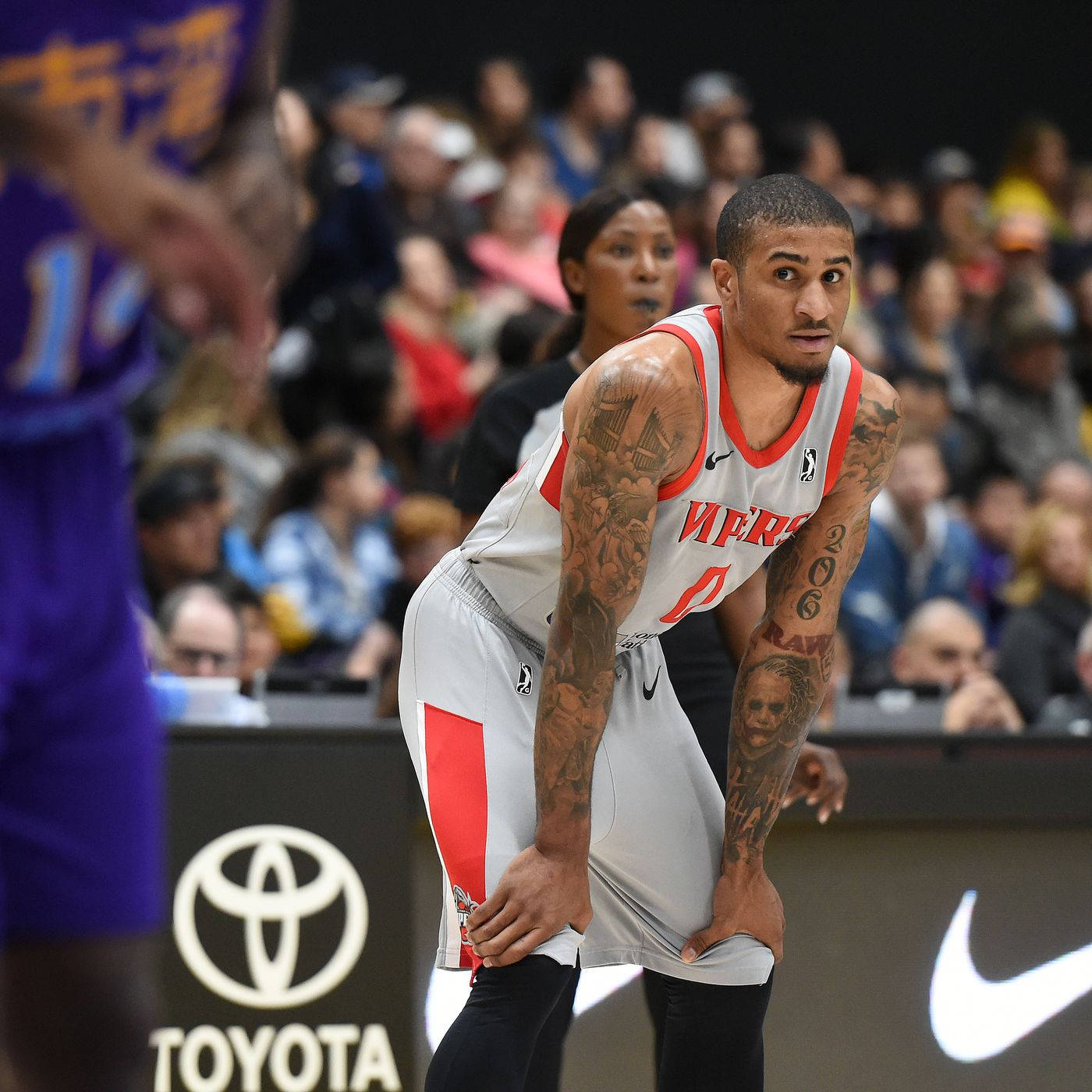 NBA 桌布 壁紙 — 一位專注的籃球運動員，手臂上有刺青，穿著白色和紅色球衣，在激烈的比賽中身體前傾。