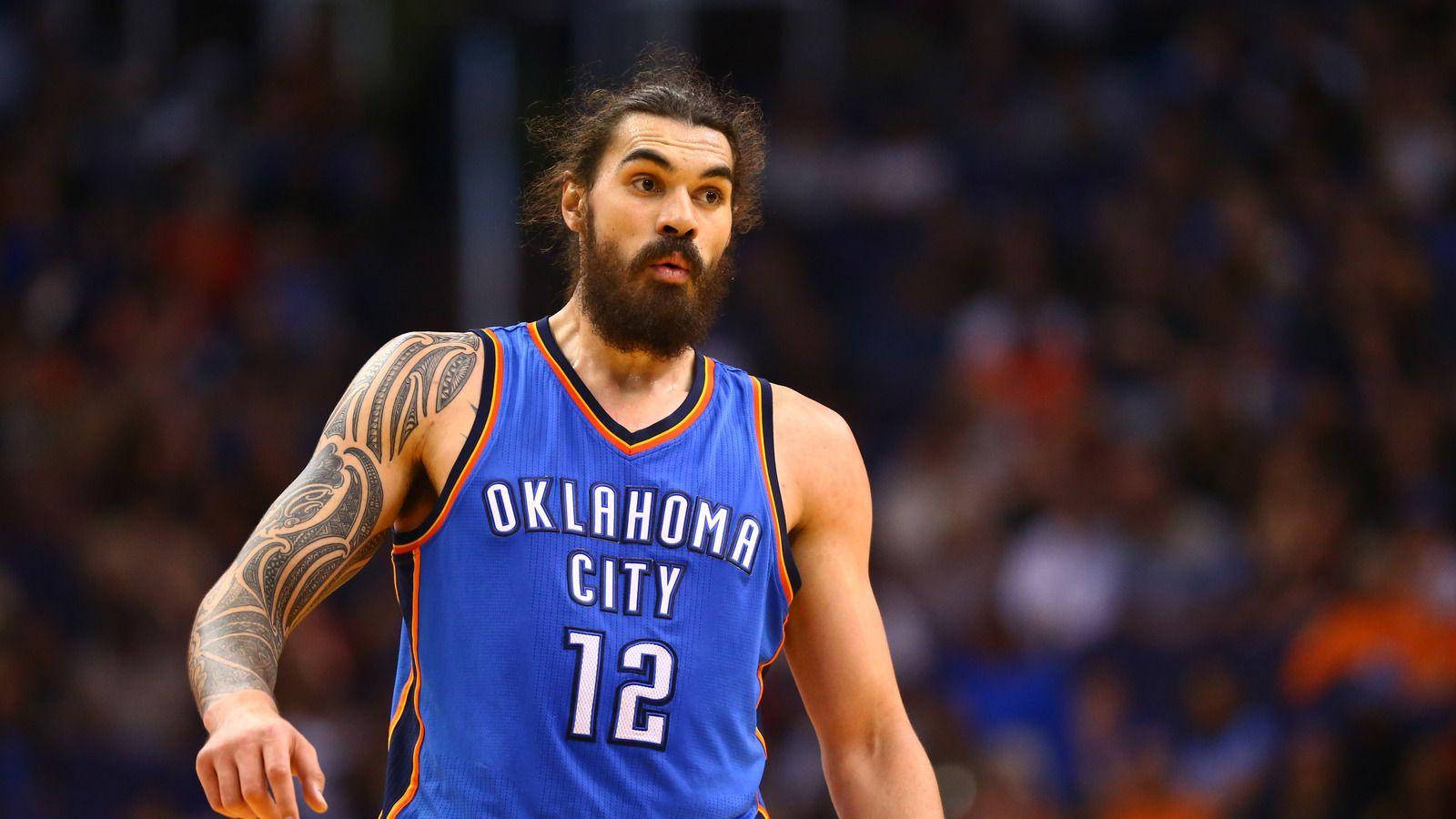 Steven Adams 桌布 壁紙 — 一位專注的籃球運動員，留著鬍鬚，手臂有刺青，身穿奧克拉荷馬城球衣比賽中。