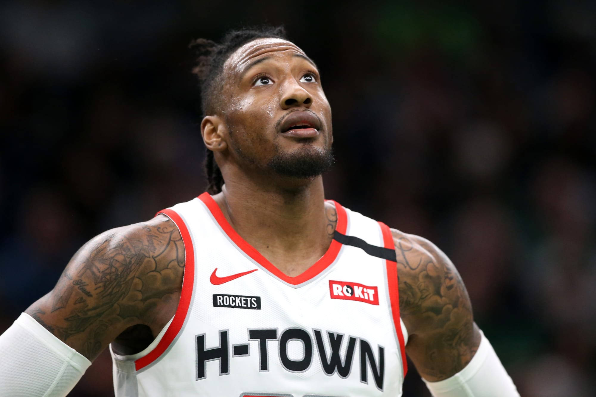 robert covington 桌布 壁紙 — 一位專注的籃球運動員，身穿白色H-Town球衣，帶有刺青，在比賽中於場館燈光下向上凝視。
