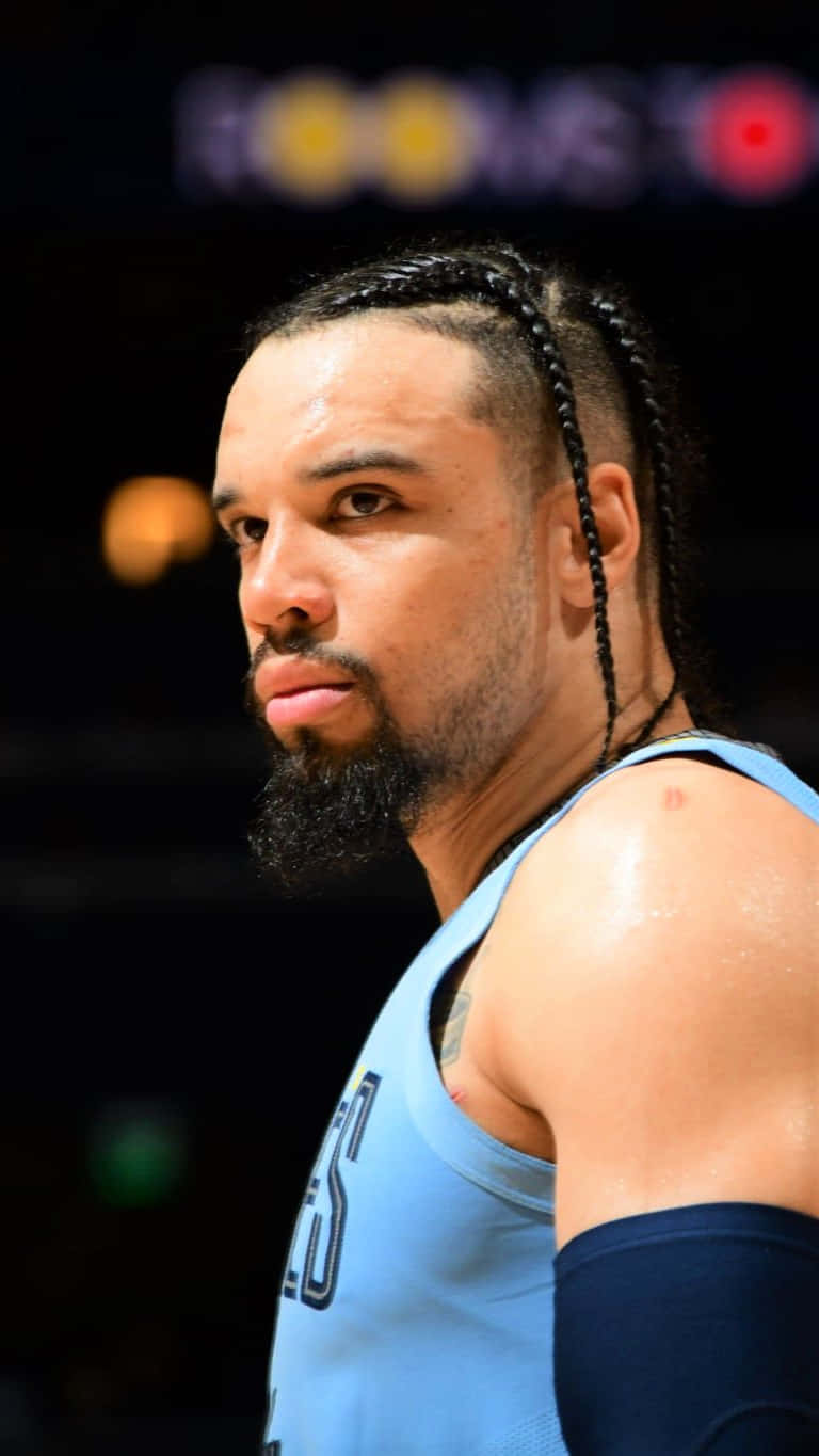 Dillon Brooks 桌布 壁紙 — 一位專注的籃球運動員，辮子頭髮和鬍鬚，在場館燈光下穿著淺藍色球衣。