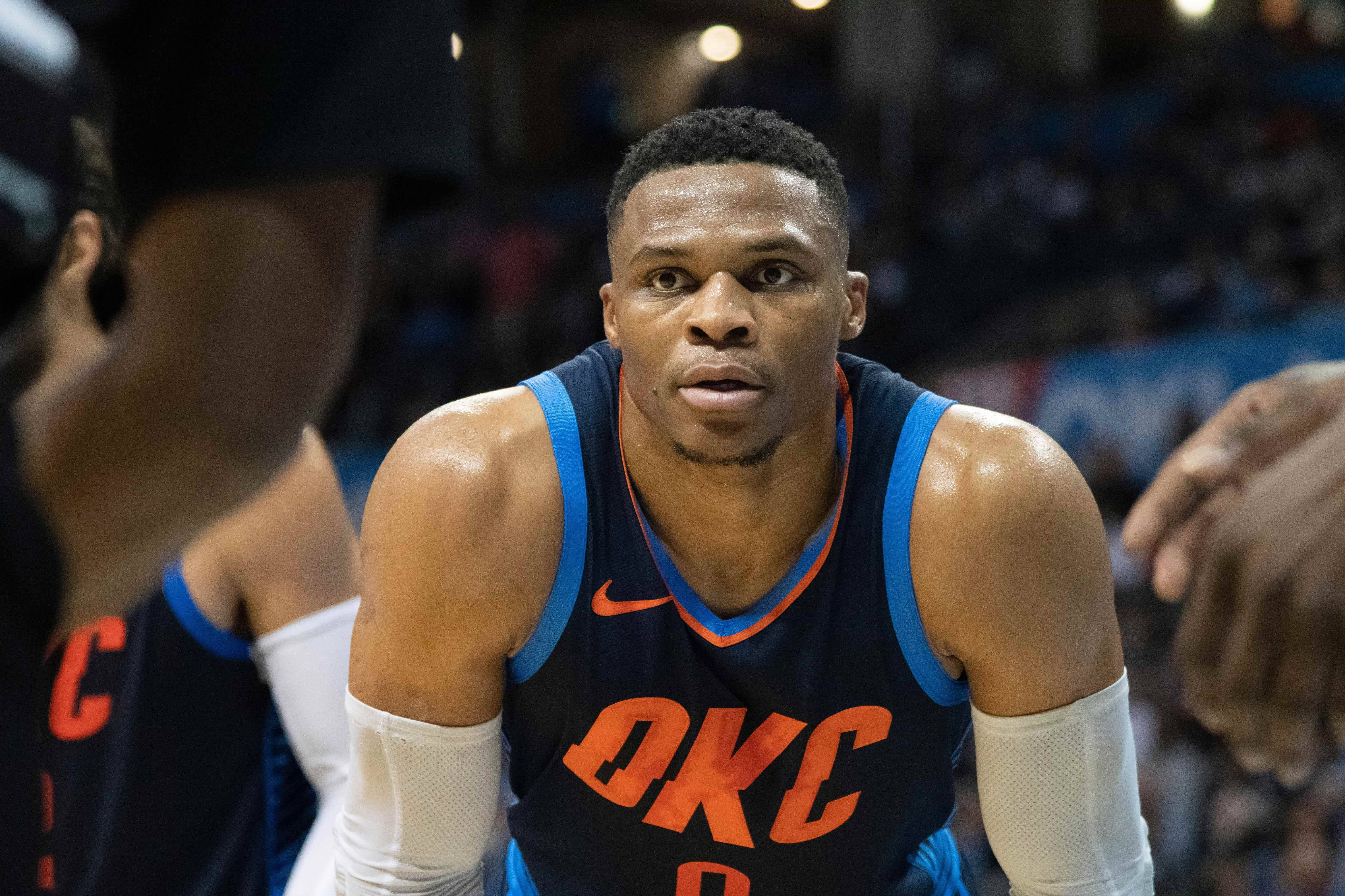 Westbrook 桌布 壁紙 — 一位專注的籃球運動員穿著OKC球衣，在明亮的場館燈光下於比賽中向前傾身。