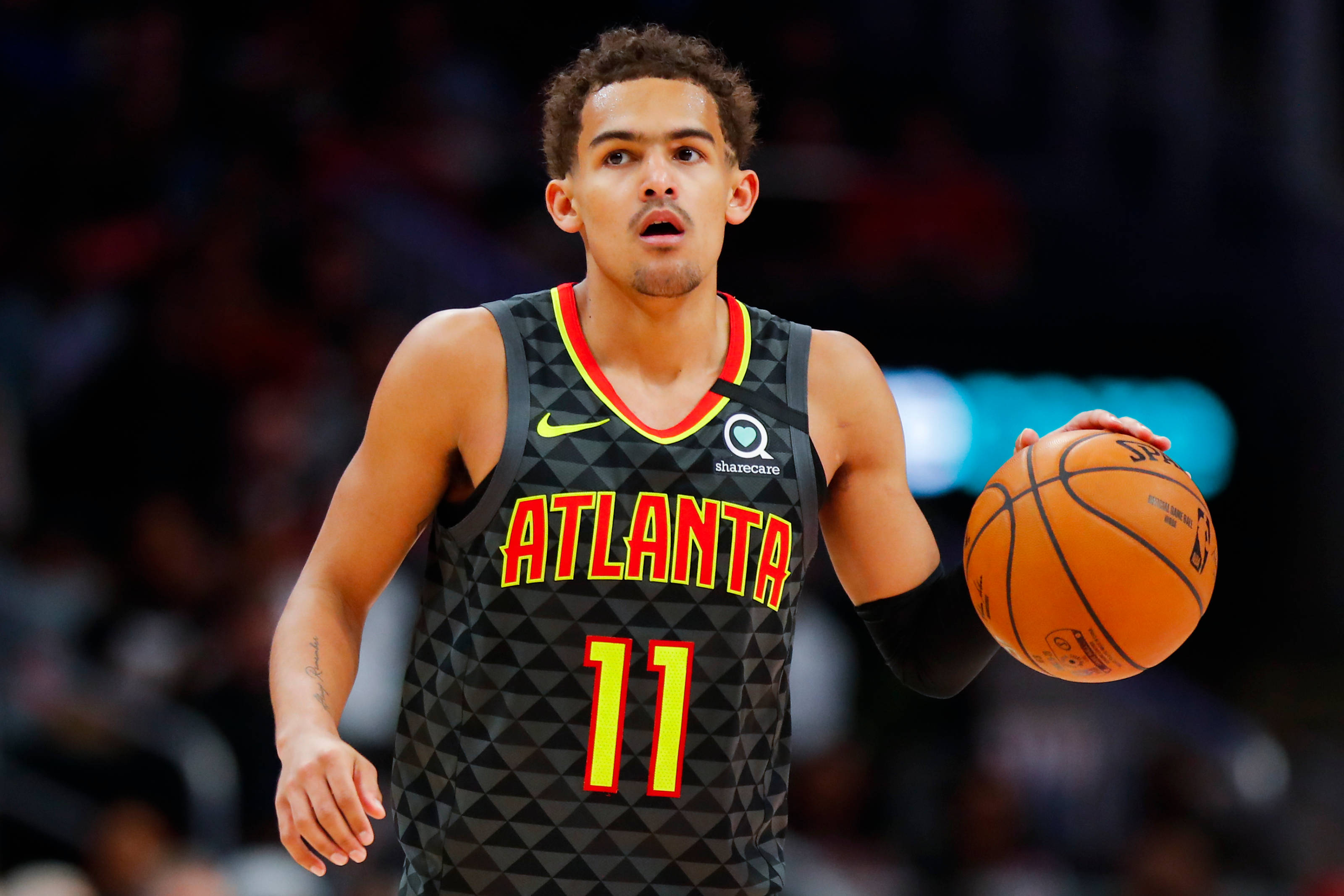 Hawks 桌布 壁紙 — 一位專注的籃球運動員穿著亞特蘭大球衣，在明亮的場館燈光下比賽中運球。