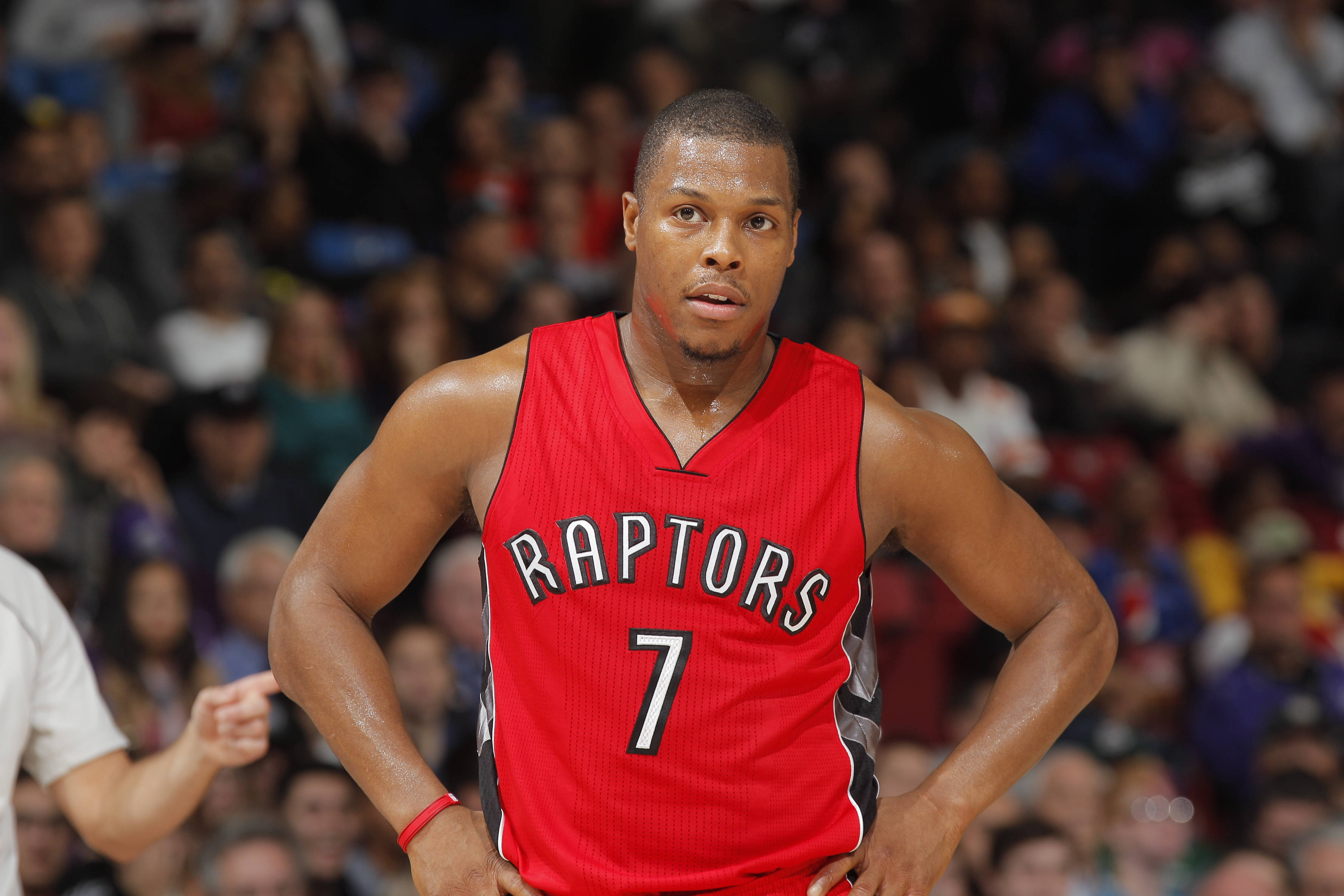 Lowry 桌布 壁紙 — 一位專注的籃球運動員穿著紅色Raptors球衣，在比賽中雙手叉腰站立，身後是模糊的人群。