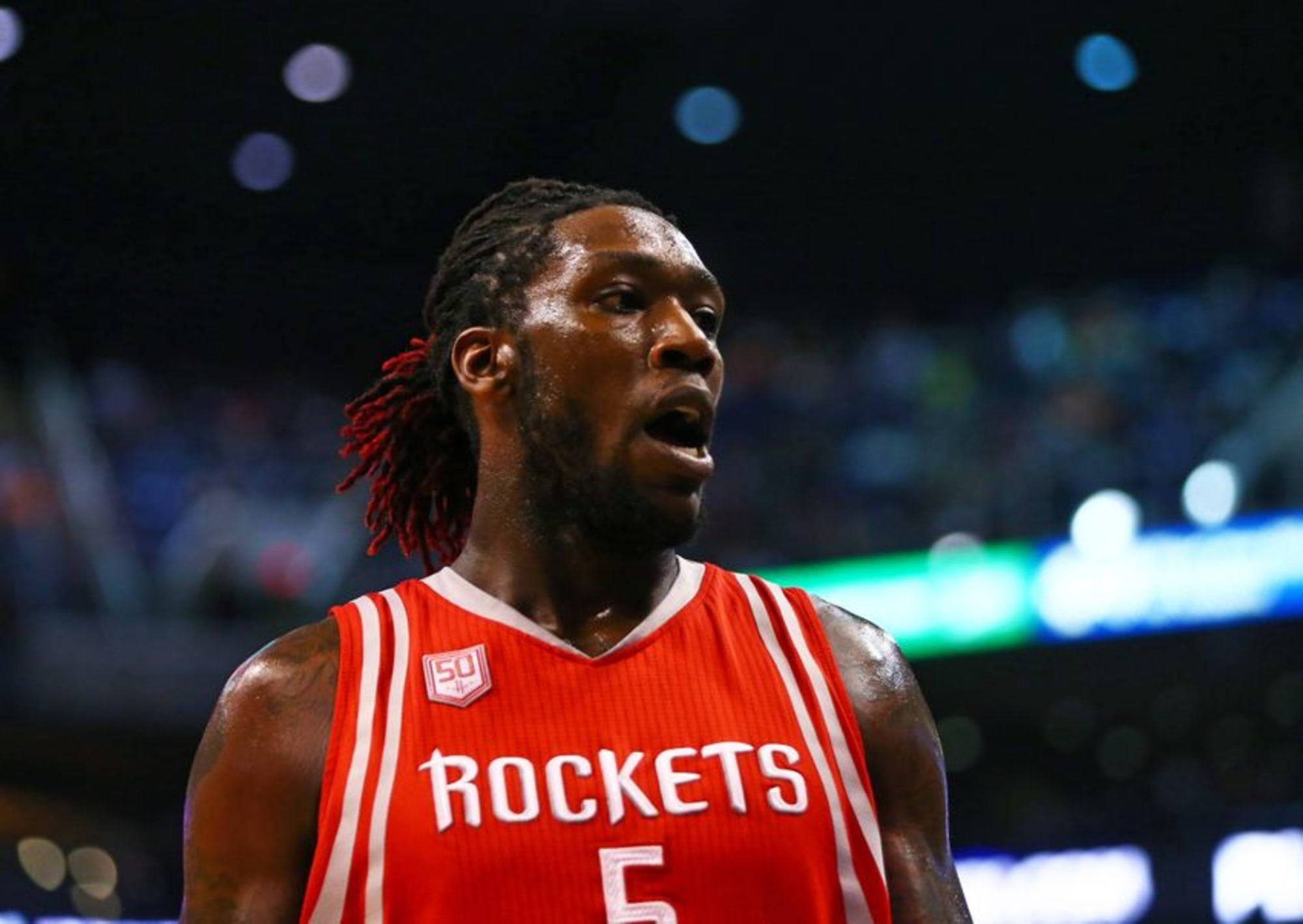 montrezl harrell 桌布 壁紙 — 一位專注的籃球運動員穿著紅色火箭隊5號球衣，在場館燈光下比賽中凝視著。