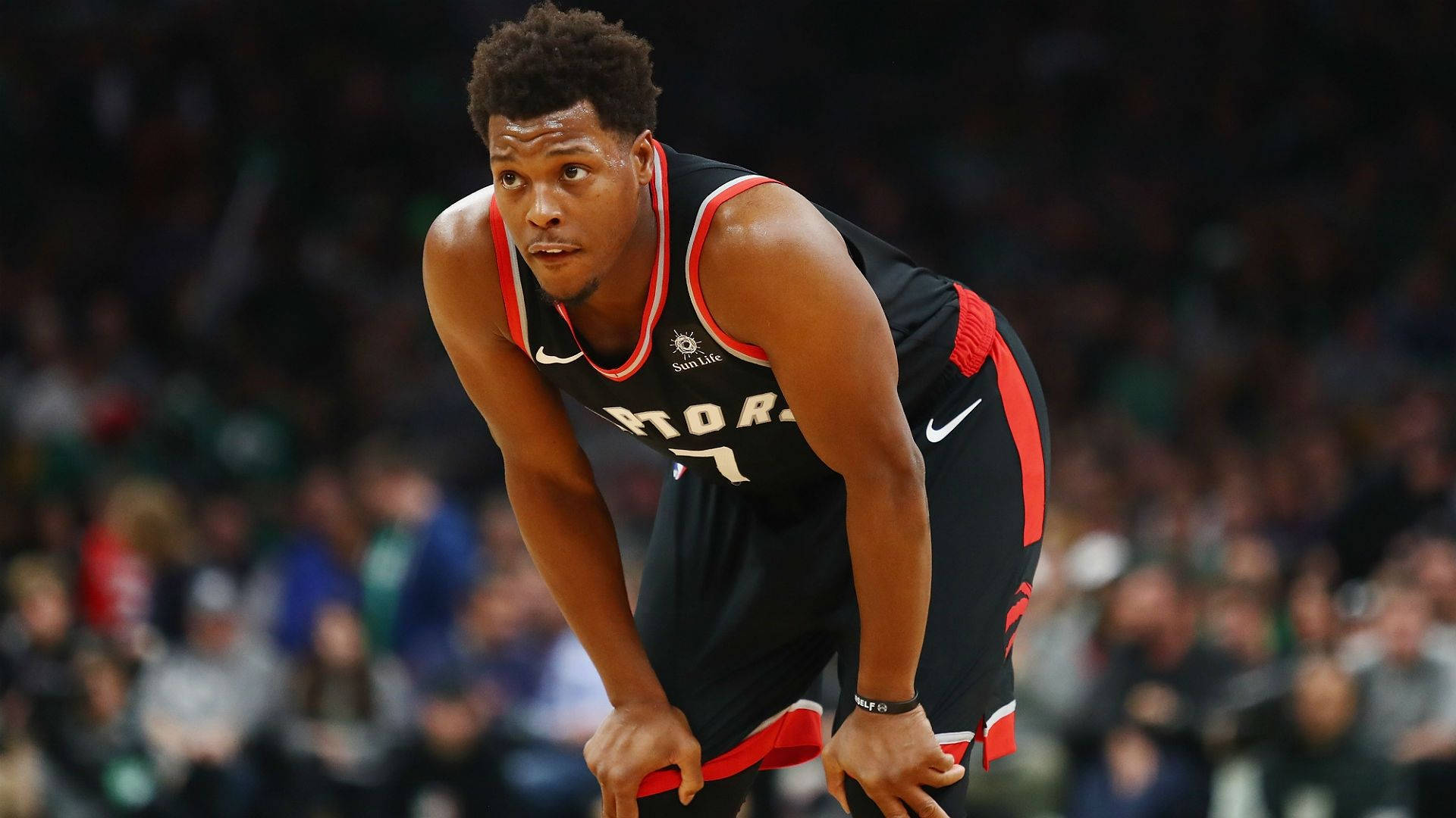 Lowry 桌布 壁紙 — 一位專注的籃球運動員身穿多倫多暴龍隊球衣，在場館燈光下於激烈比賽中低蹲。