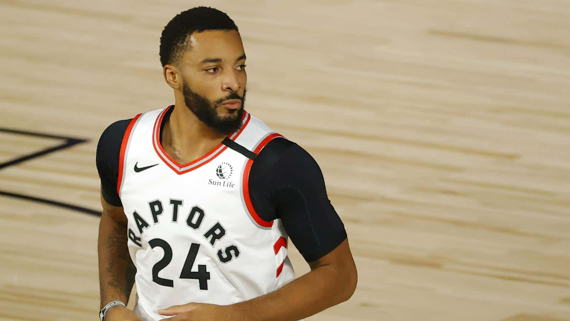NBA 桌布 壁紙 — 一位專注的籃球運動員身穿多倫多暴龍隊球衣，在比賽期間站在拋光木地板上。