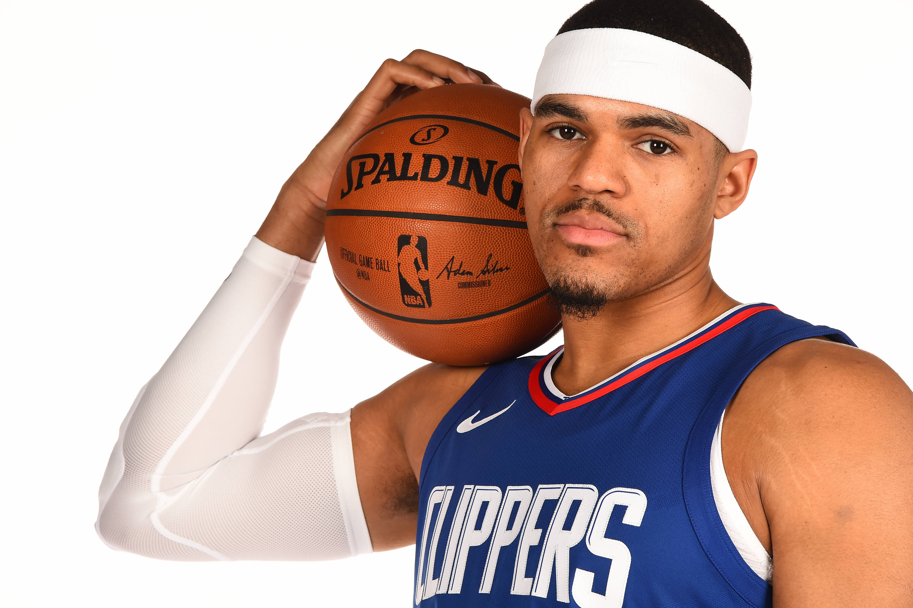 NBA 桌布 壁紙 — 一位專注的籃球運動員身穿快艇隊球衣，在純白背景前手持Spalding籃球。