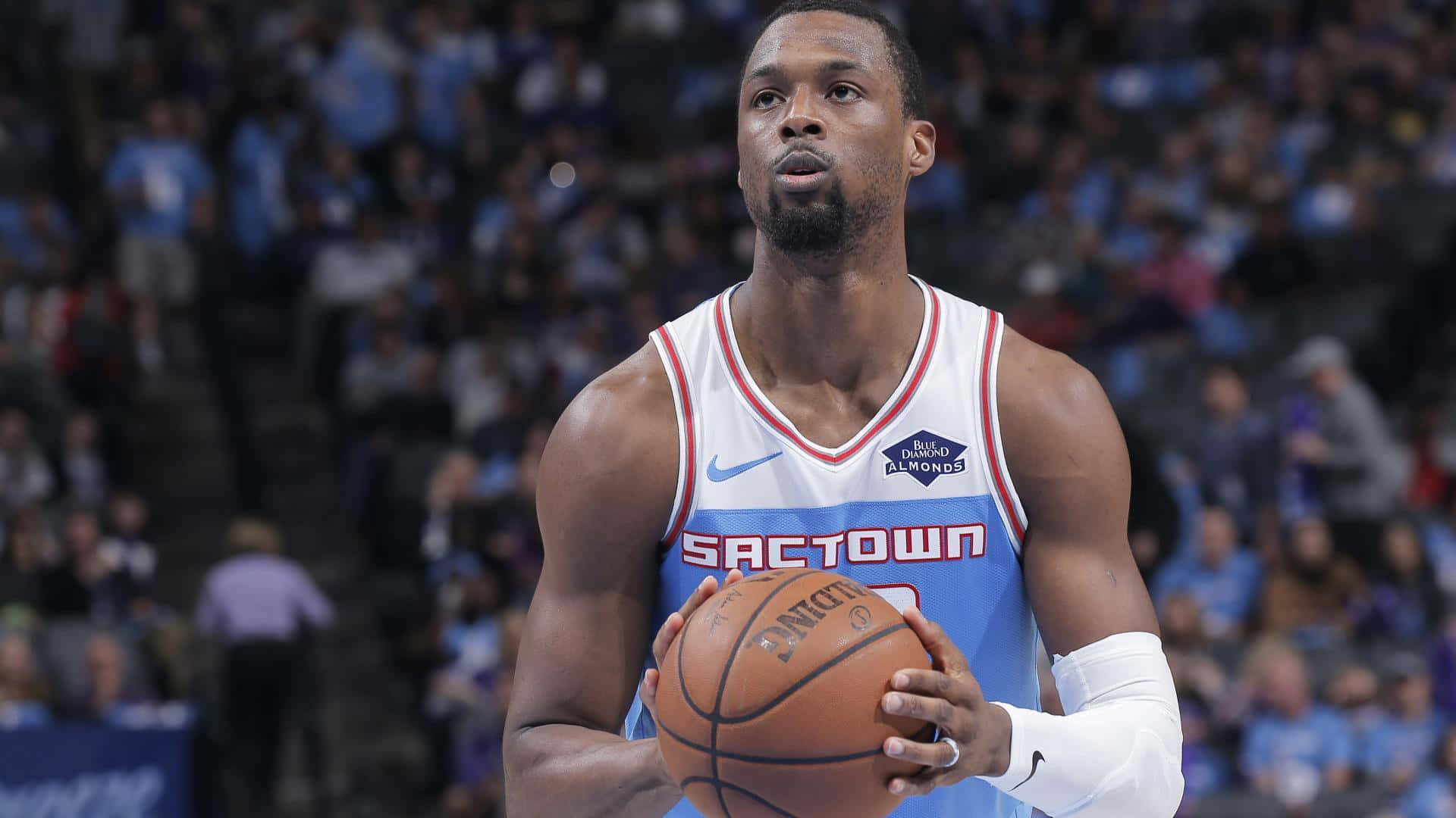 NBA 桌布 壁紙 — 一位專注的籃球運動員身穿沙加緬度國王隊球衣，在比賽中持球，背景是模糊的人群。