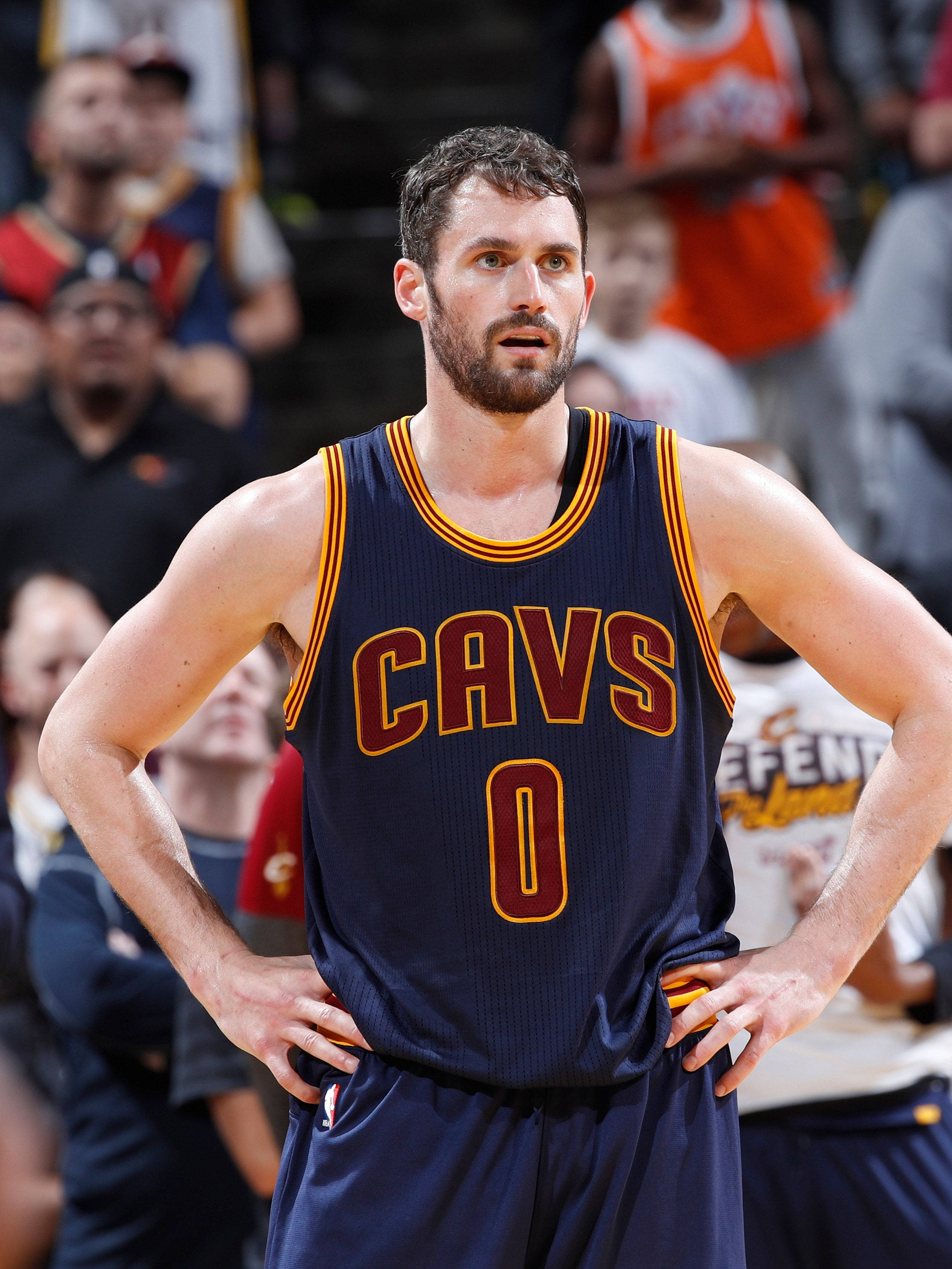 Kevin Love 桌布 壁紙 — 一位專注的籃球運動員身穿海軍藍CAVS球衣，背號零，在比賽中雙手叉腰站立。