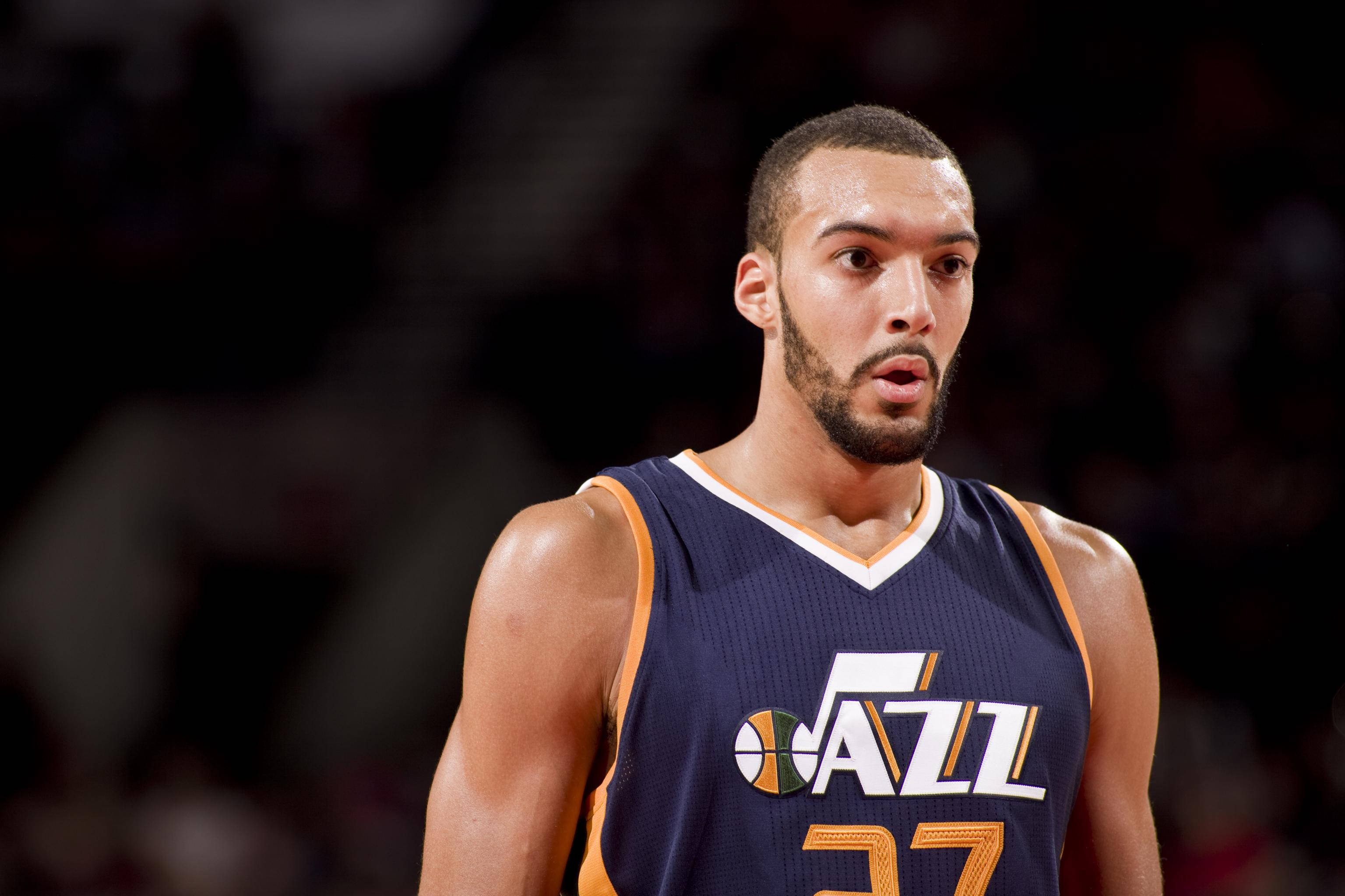 Rudy 桌布 壁紙 — 一位專注的籃球運動員身穿深藍色 Jazz 球衣，帶橙色飾邊，在明亮的場館燈光下準備比賽。