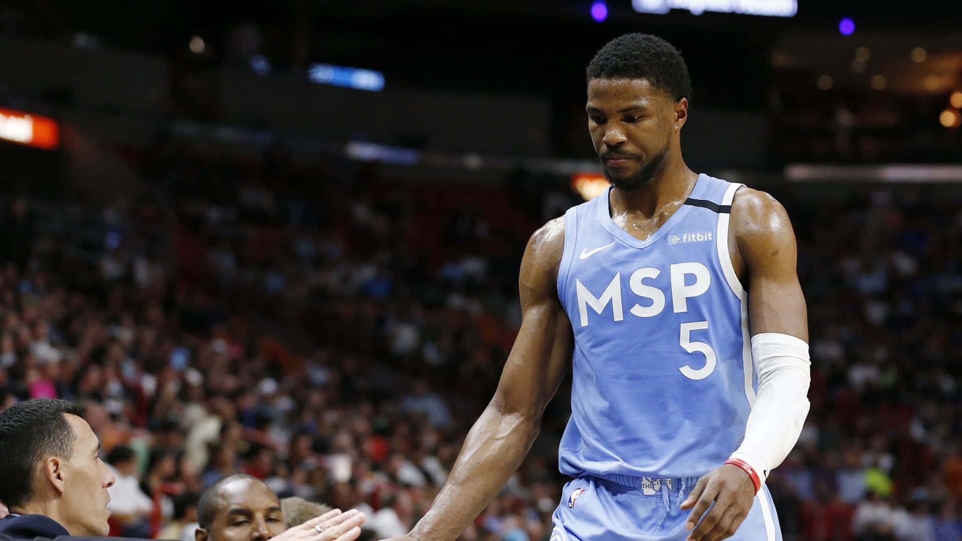 身穿藍色球衣的籃球運動員在比賽中與教練握手。 — NBA 壁紙