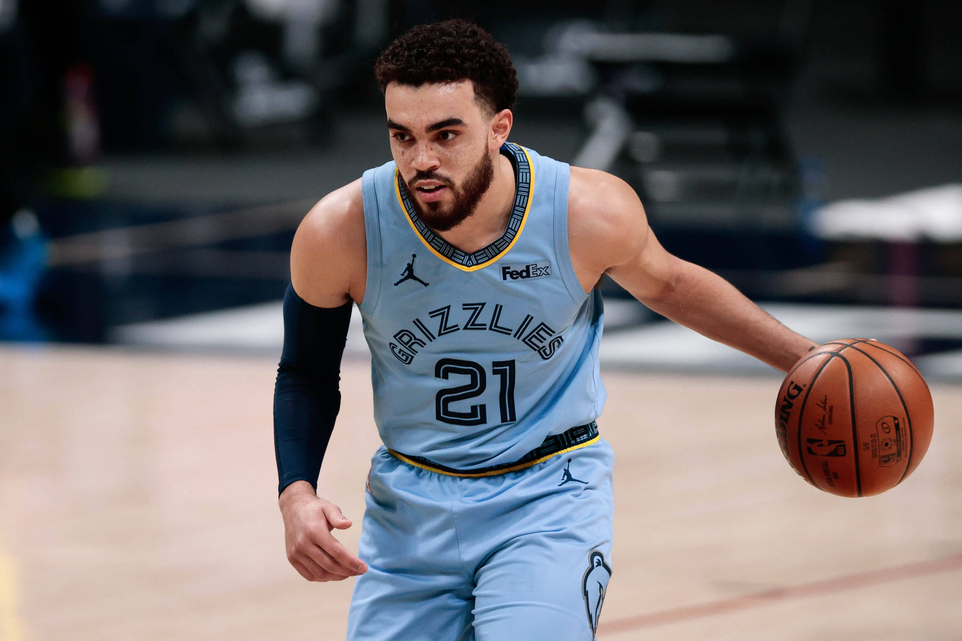Grizzlies 桌布 壁紙 — 一位專注的籃球運動員身穿淺藍色灰熊隊球衣，在拋光球場上進行激烈比賽時運球。