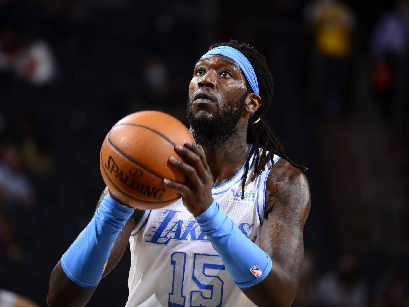 montrezl harrell 桌布 壁紙 — 一位專注的籃球運動員身穿湖人隊球衣，在場館燈光下準備投擲Spalding籃球。