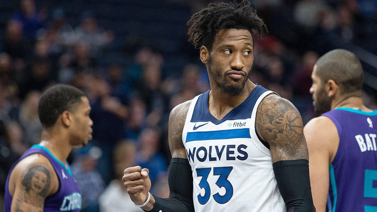 robert covington 桌布 壁紙 — 一位專注的籃球運動員身穿狼隊球衣，身上有刺青，在比賽中握緊拳頭，隊友在附近。
