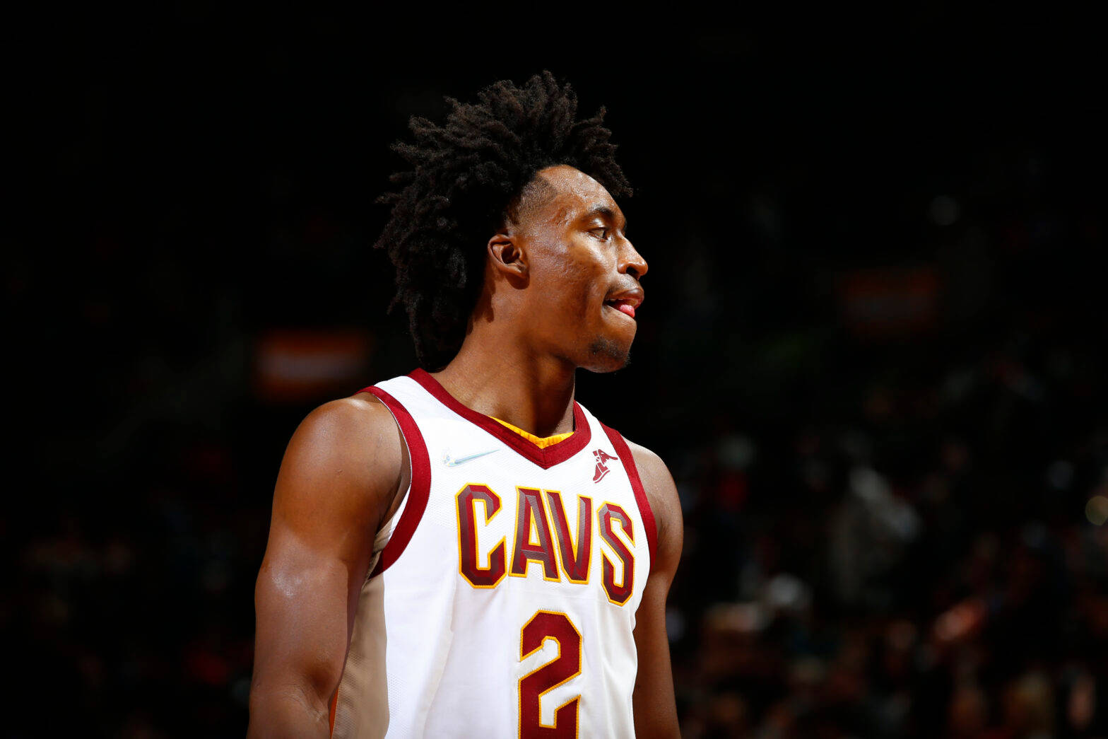 NBA 桌布 壁紙 — 一位專注的籃球運動員身穿白色Cavs球衣，背號2號，站在燈光昏暗的球場上，目光向上凝視。