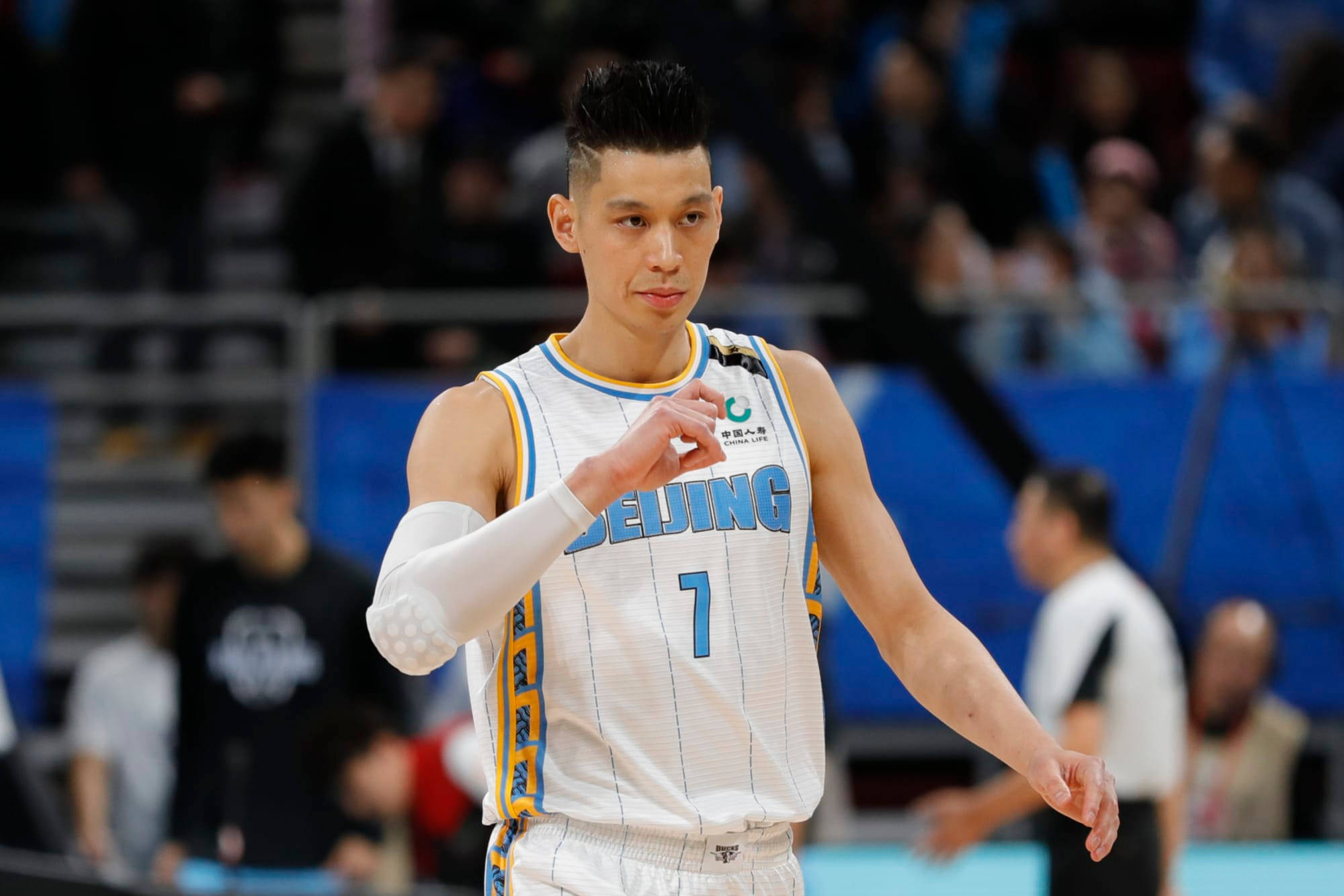 Lin 桌布 壁紙 — 一位專注的籃球運動員身穿白色北京球衣，號碼7，在明亮的場館燈光下比賽中做手勢。