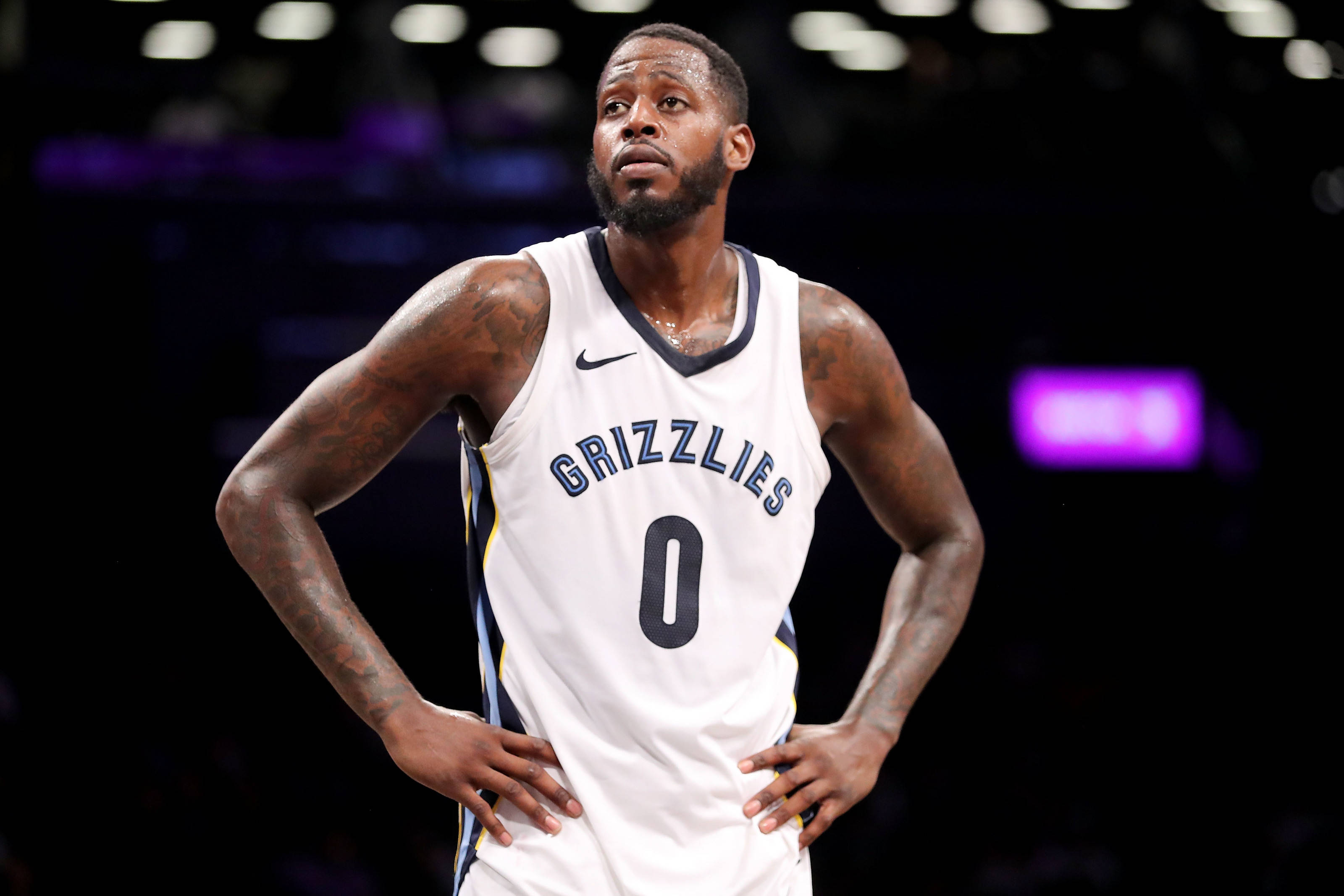 Grizzlies 桌布 壁紙 — 一位專注的籃球運動員身穿白色灰熊隊球衣，號碼零，在場館燈光下雙手叉腰站立。