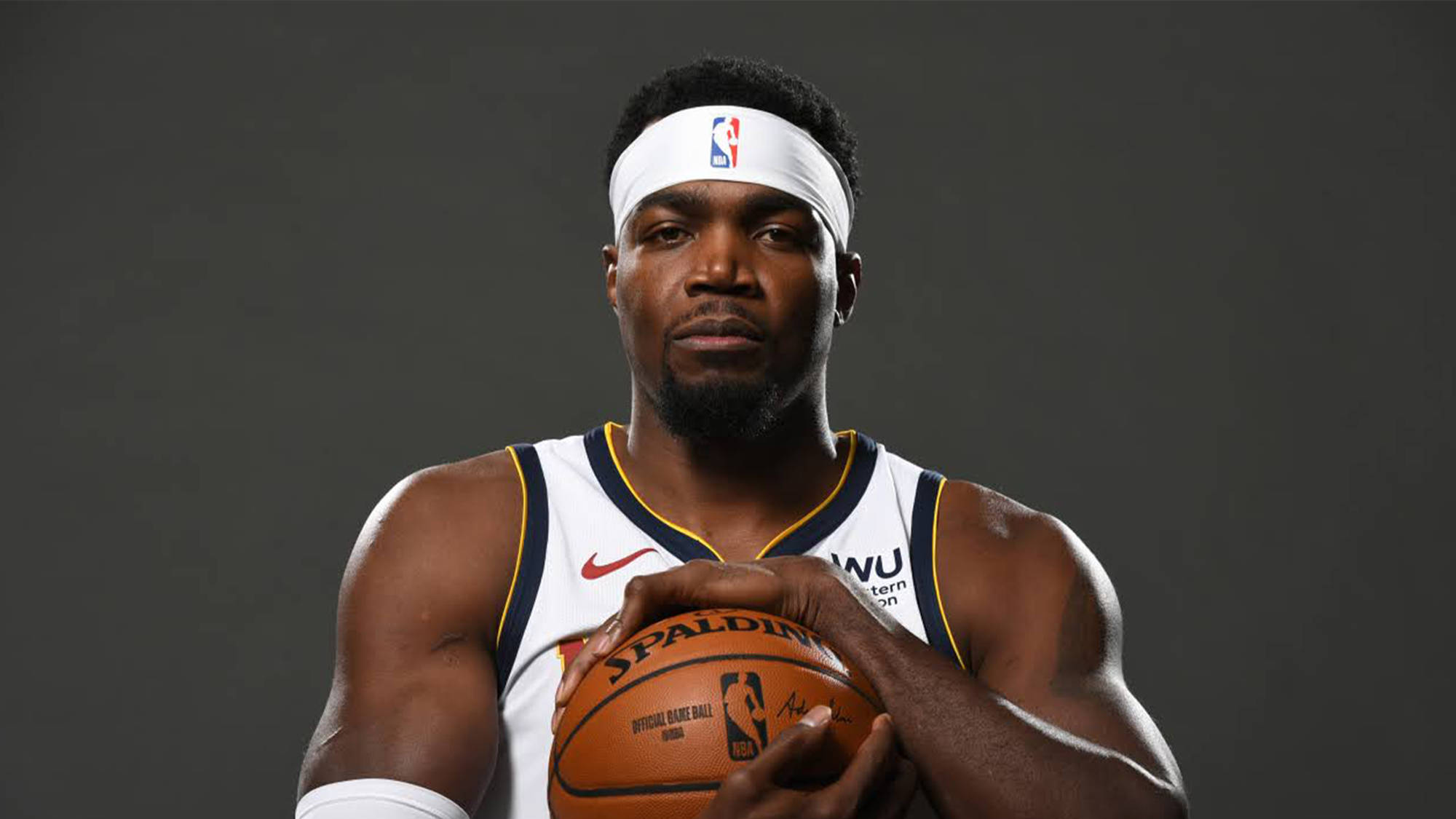 paul millsap 桌布 壁紙 — 一位專注的籃球運動員身穿白色球衣，在深色工作室背景下拿著Spalding球。