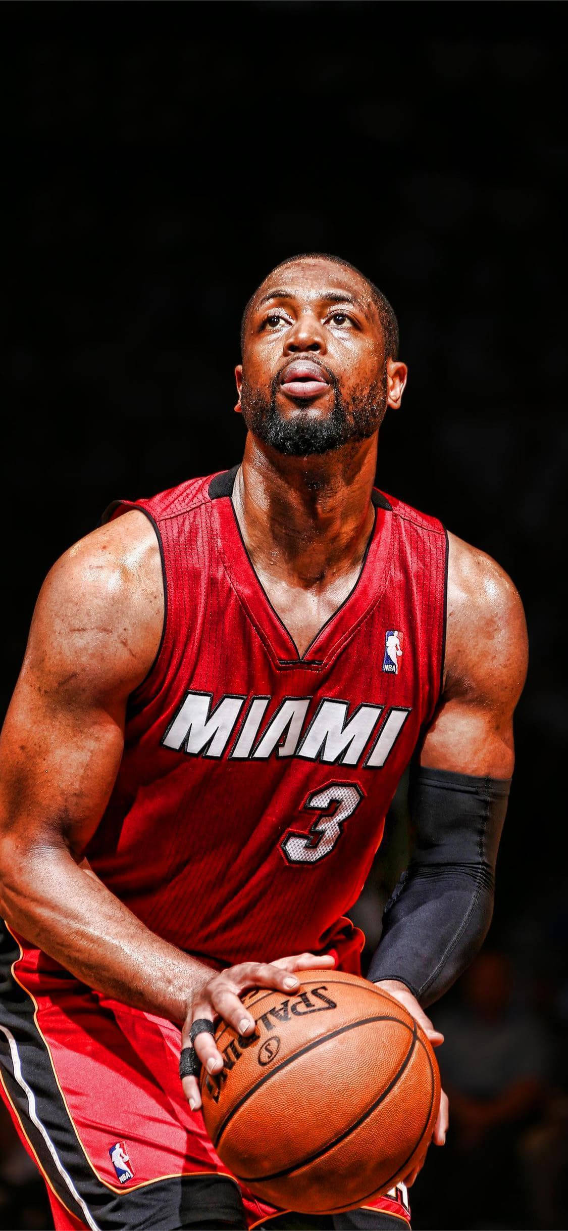 NBA 桌布 壁紙 — 一位專注的籃球運動員身穿紅色邁阿密球衣，在深色背景前持球。
